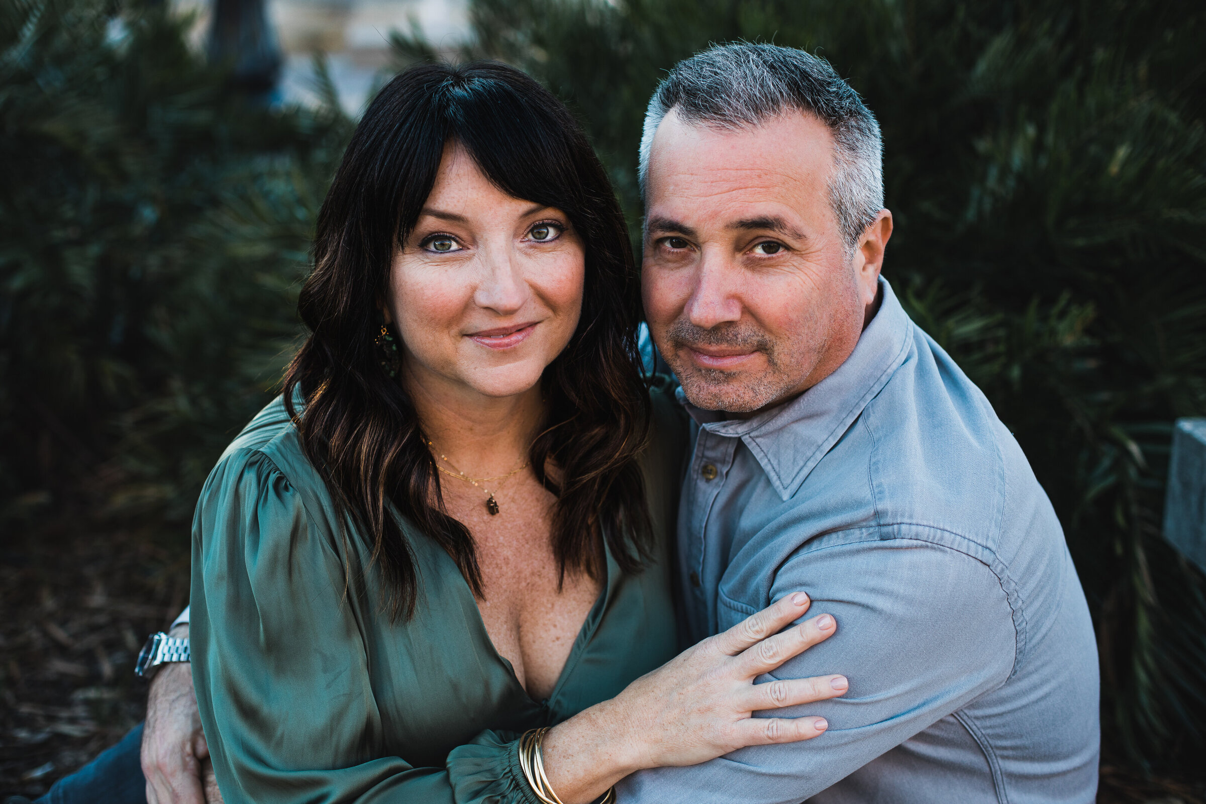 Engaged couple sitting and hugging, smiling, in urban setting