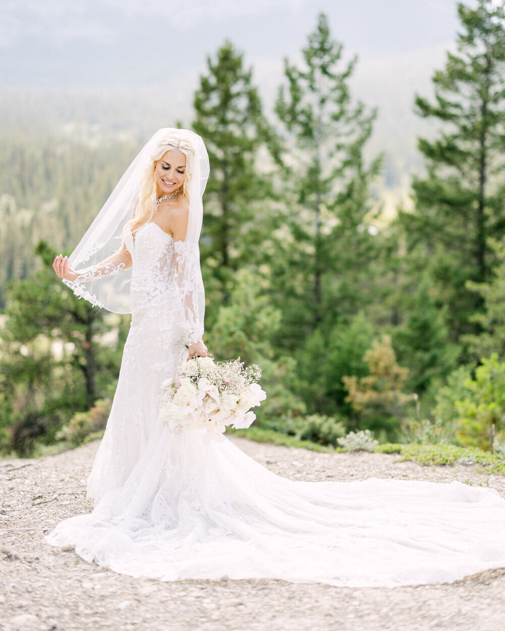 This elegant bridal portrait, captured by editorial wedding photographer Geoff Wilkings, features the bride standing gracefully with Mount Rundle and Tunnel Mountain as the breathtaking backdrop. The serene beauty of Banff National Park highlights the bride's elegance and adds a timeless touch to her wedding day.