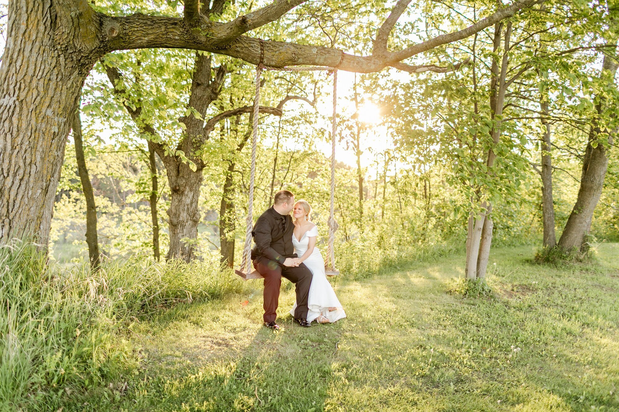 Bride and groom sitting on swing in a field, taken by wedding photographers in minneapolis