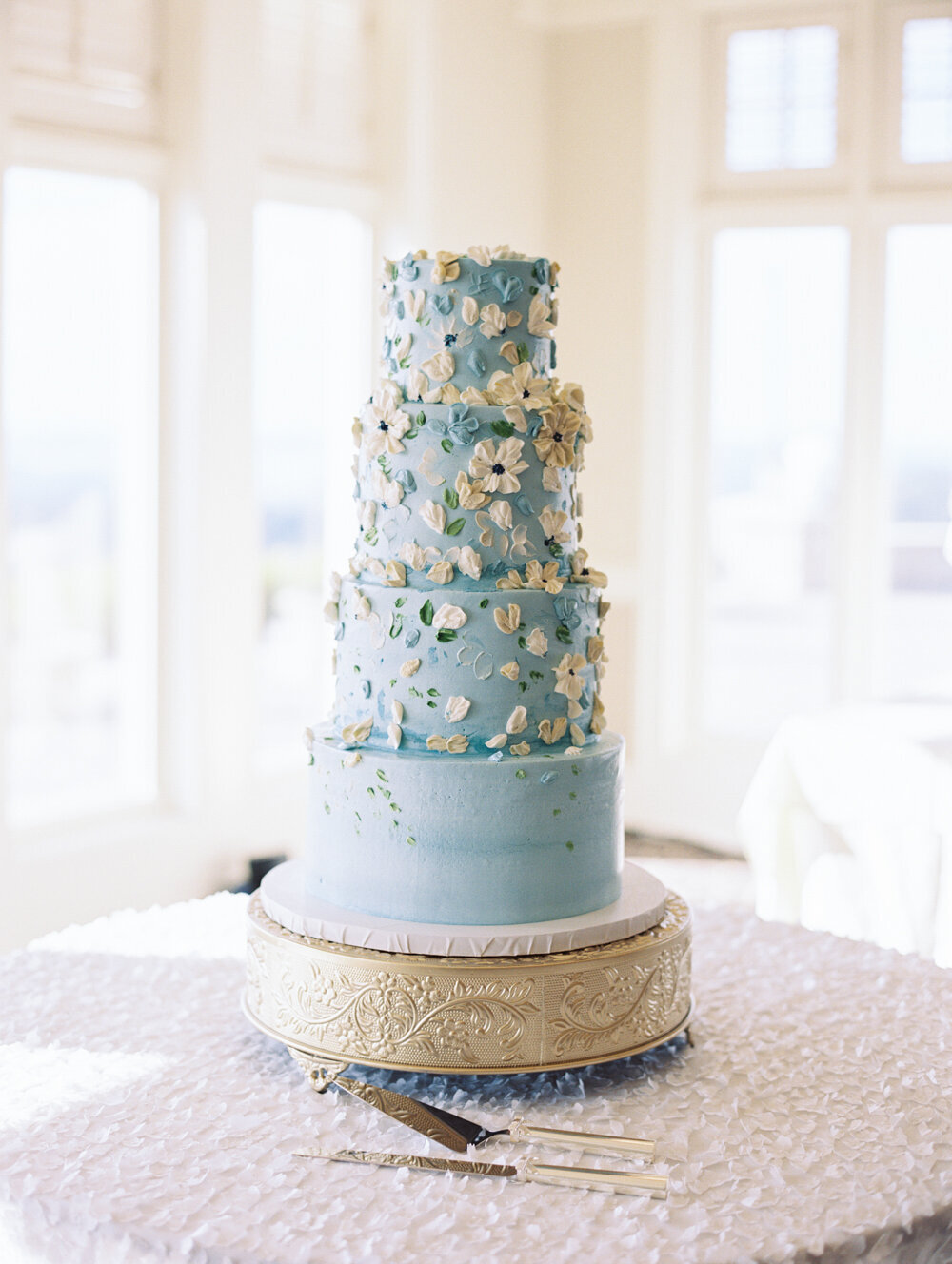 blue four tier wedding cake with textured buttercream florals