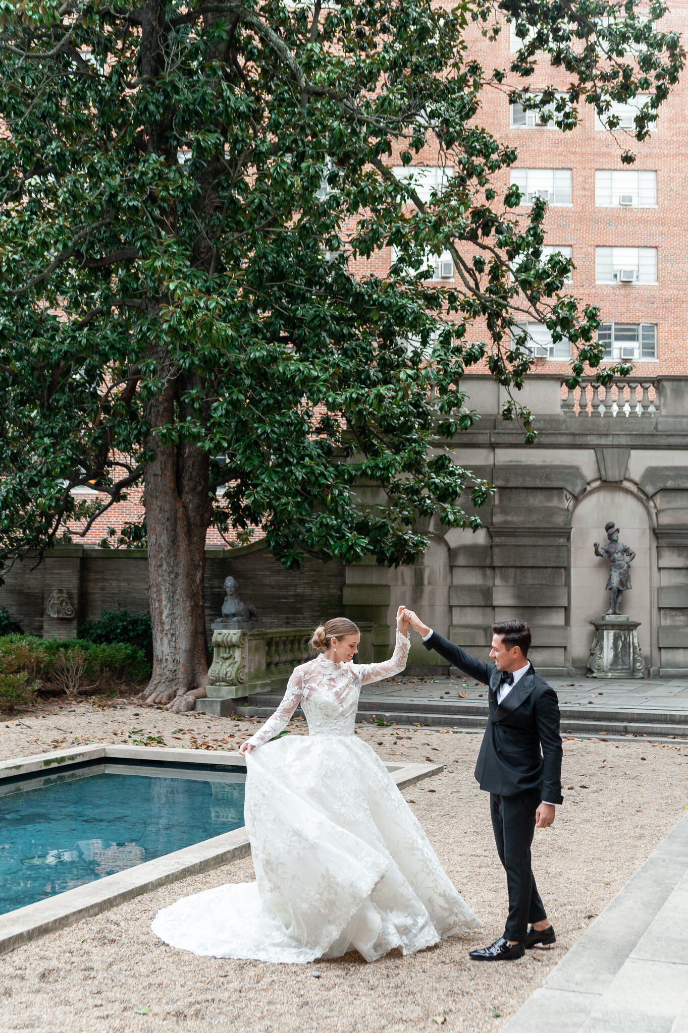 groom twirling his bride in front of a reflecting pool
