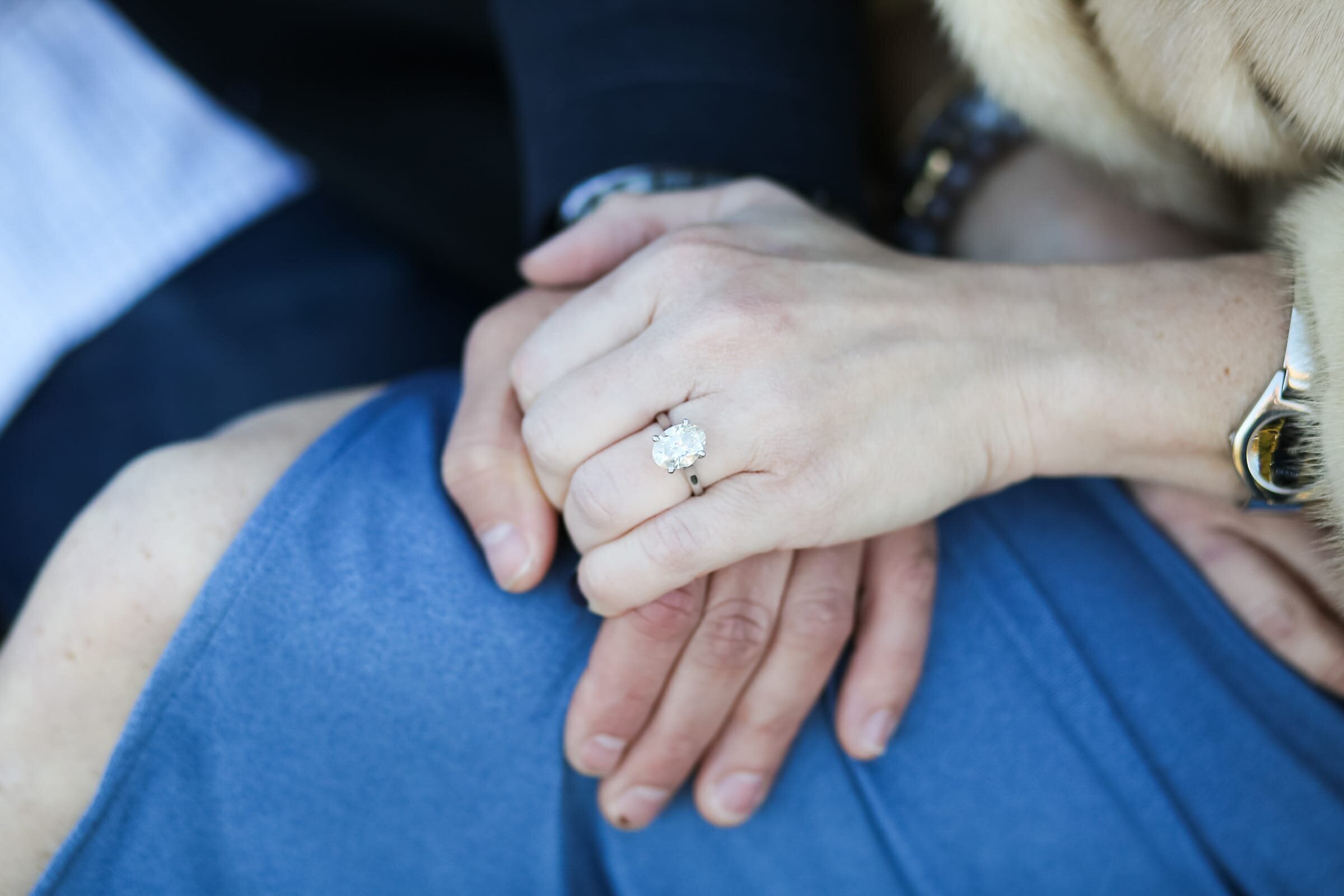 Engaged couple holding hands showing off diamond engagement ring.Engagement photographer in raleigh NC.