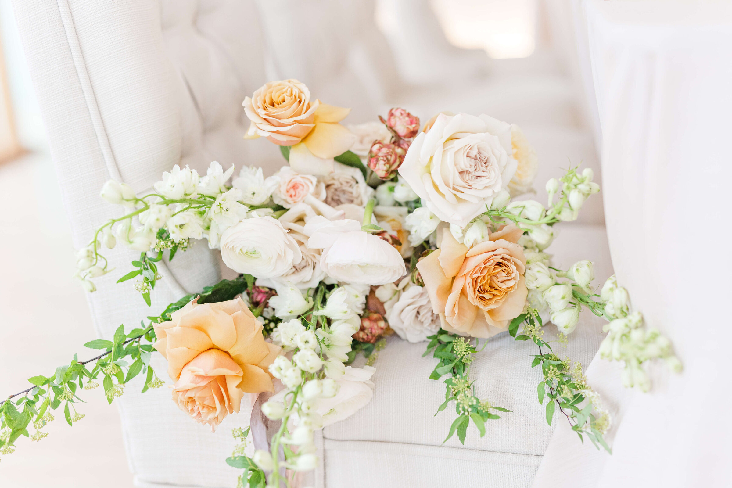 A floral bouquet sitting on a white linen chair at a wedding