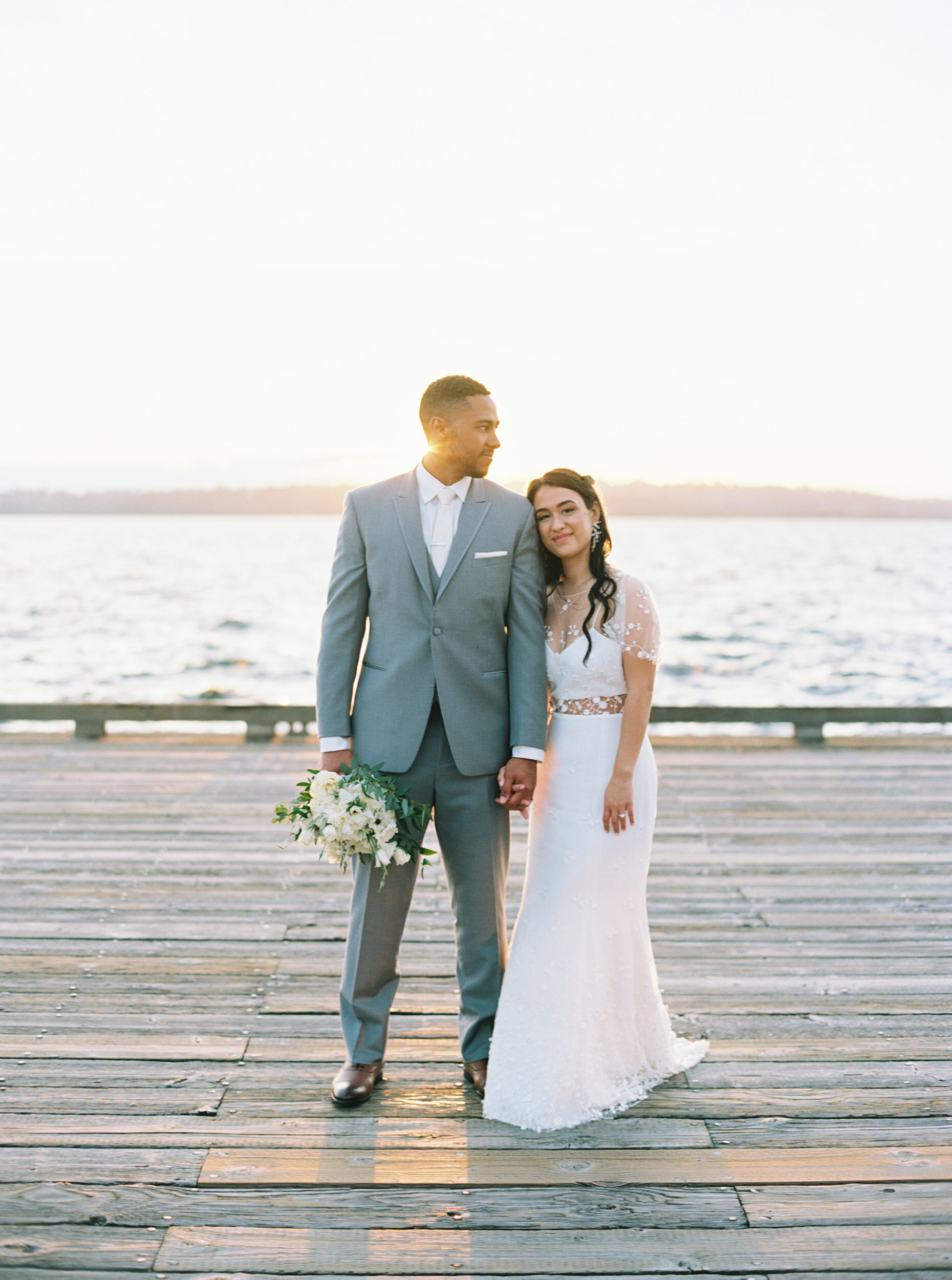 bride and groom on lake dock at golden hour