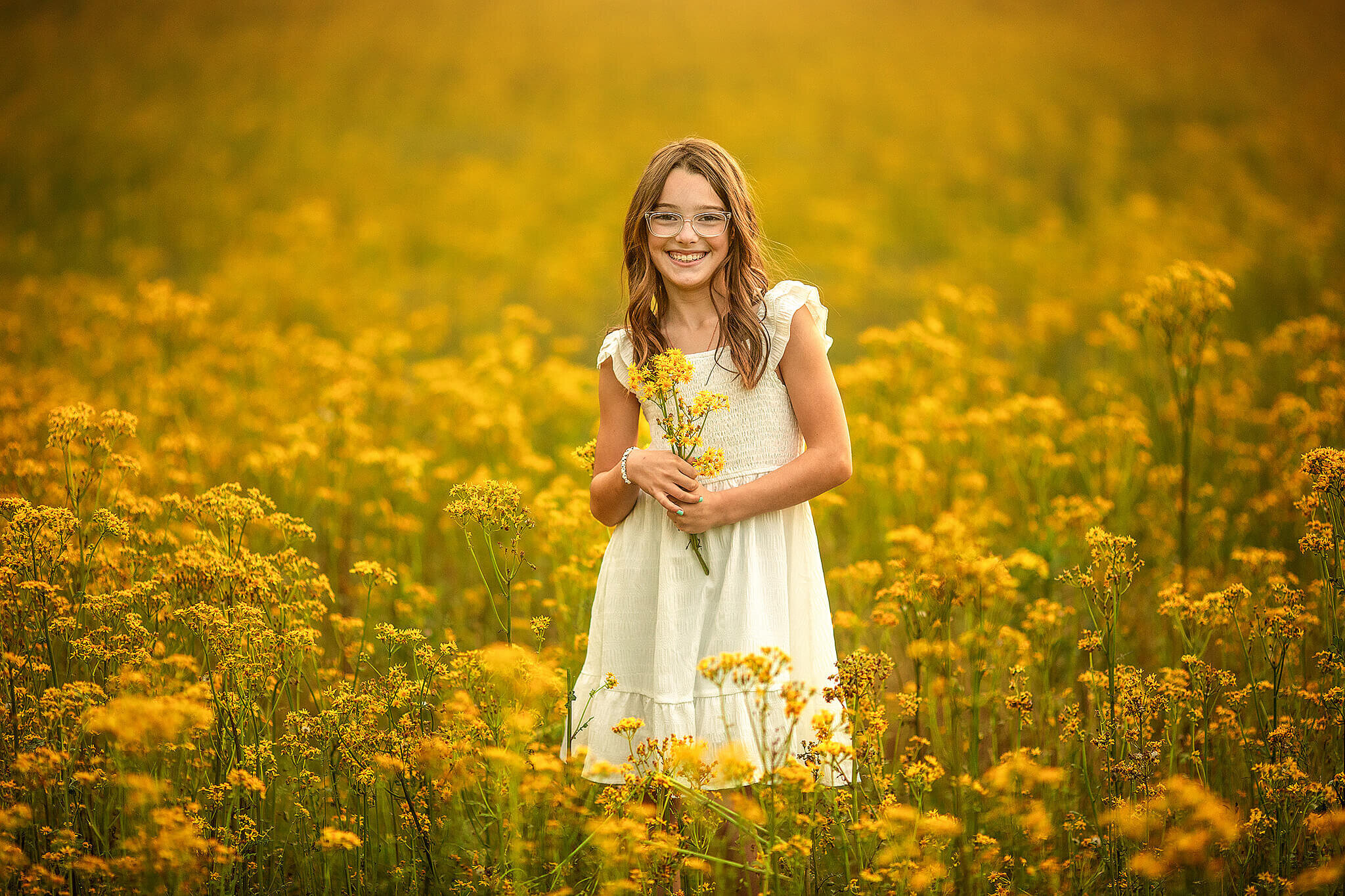 Young girl standing in a field full of pretty yellow wildflowers