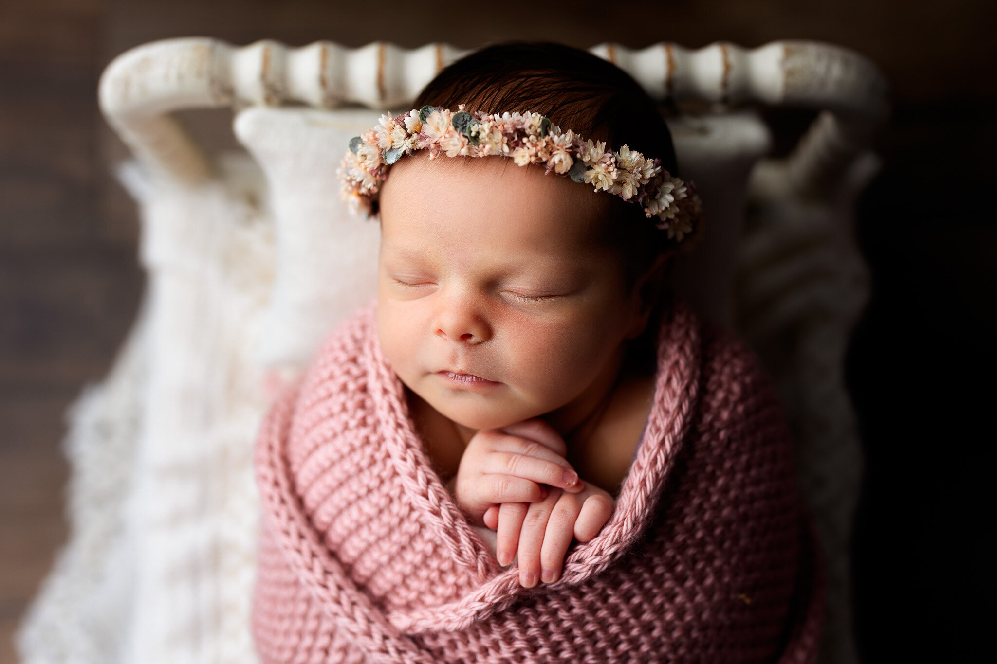 Newborn baby girl wrapped in pink with floral headband 