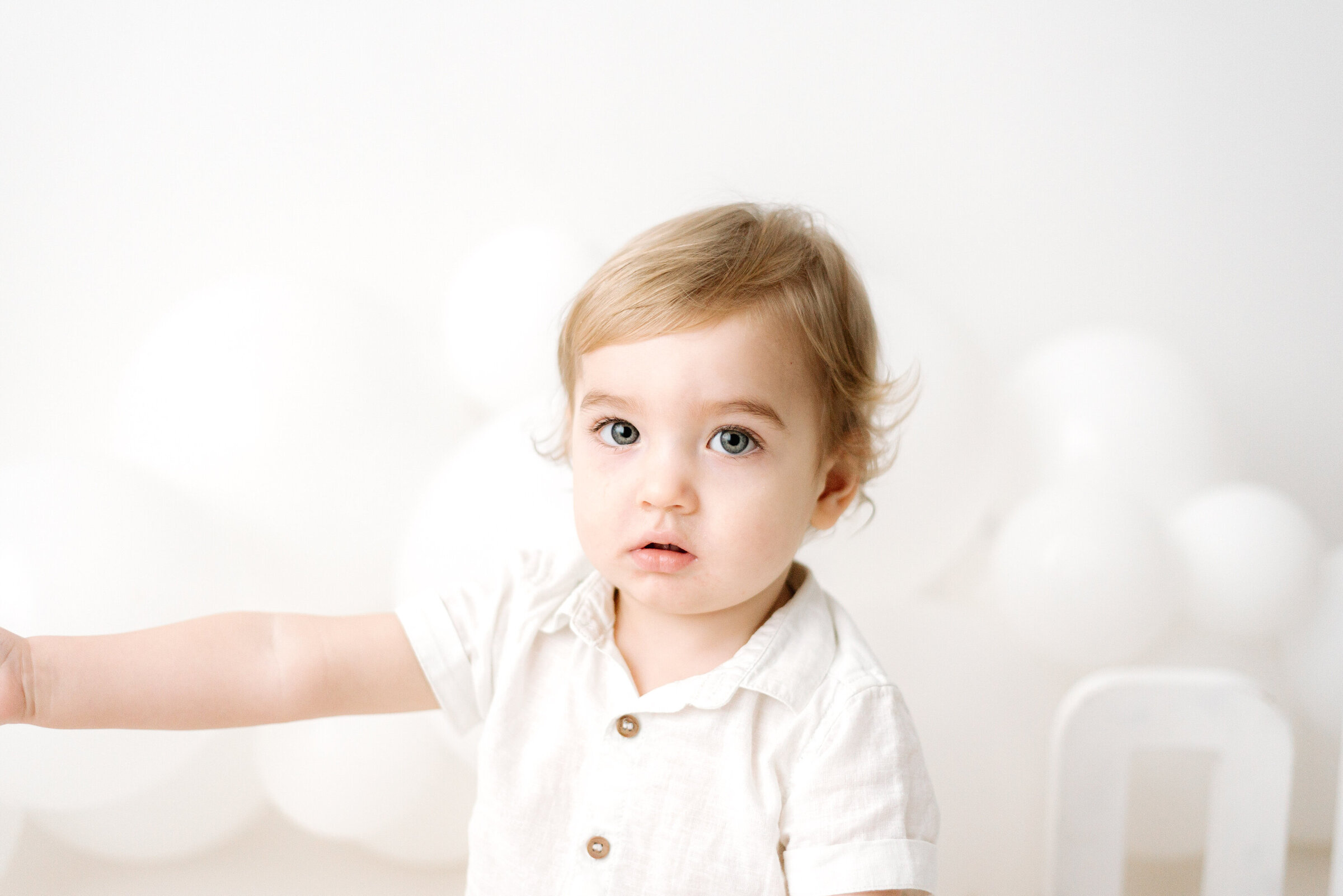 Boy looking up at the camera in front of balloons at billingshurst cake smash photoshoot