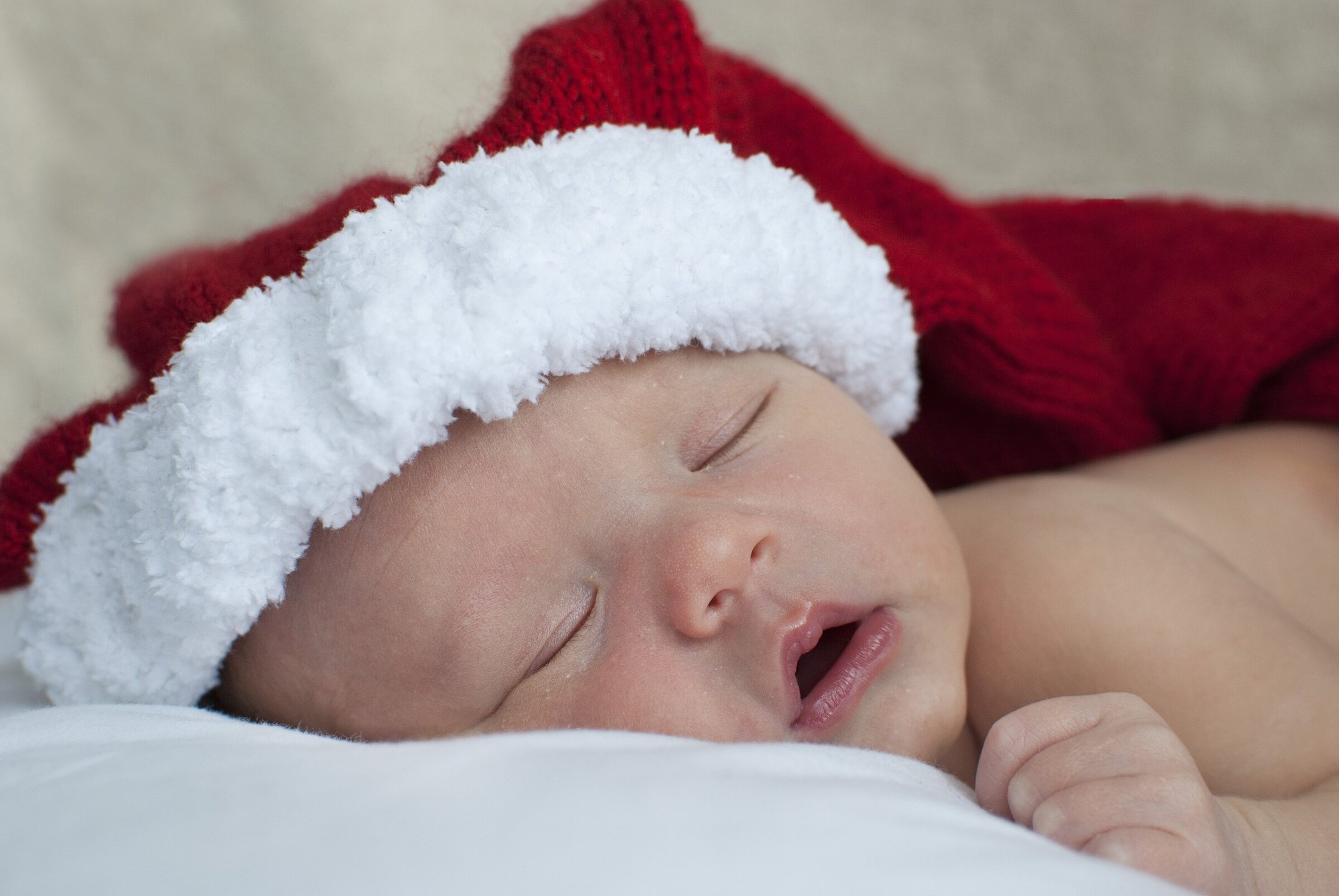 Close up of newborn sleeping whilst wearing a santa hat