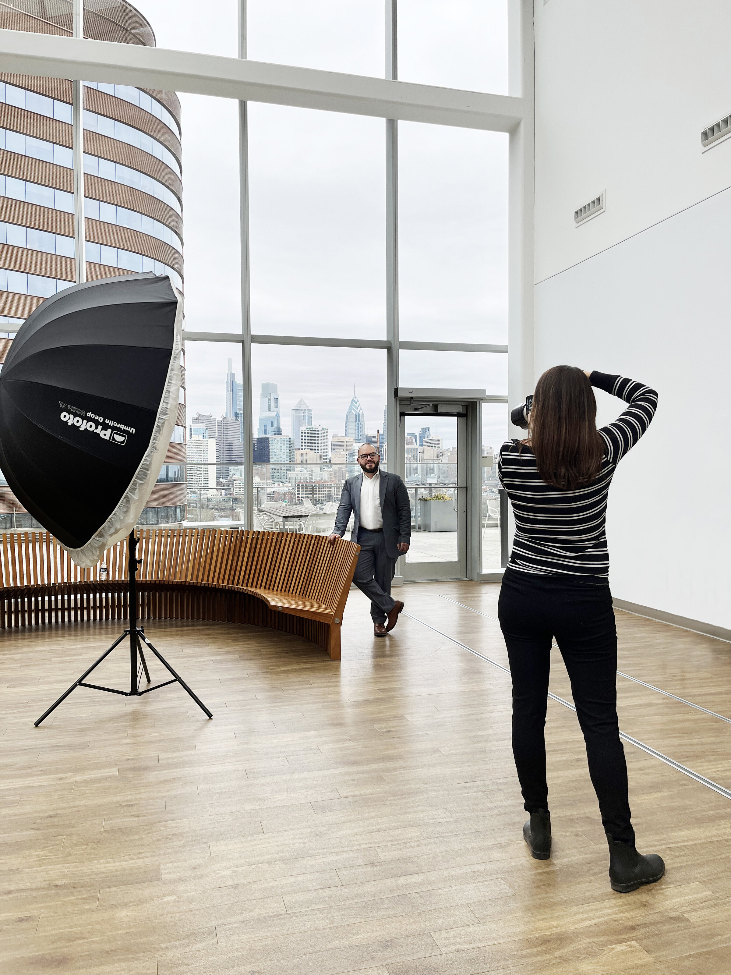 Photographer from the back photographing a man with city skyline behind him