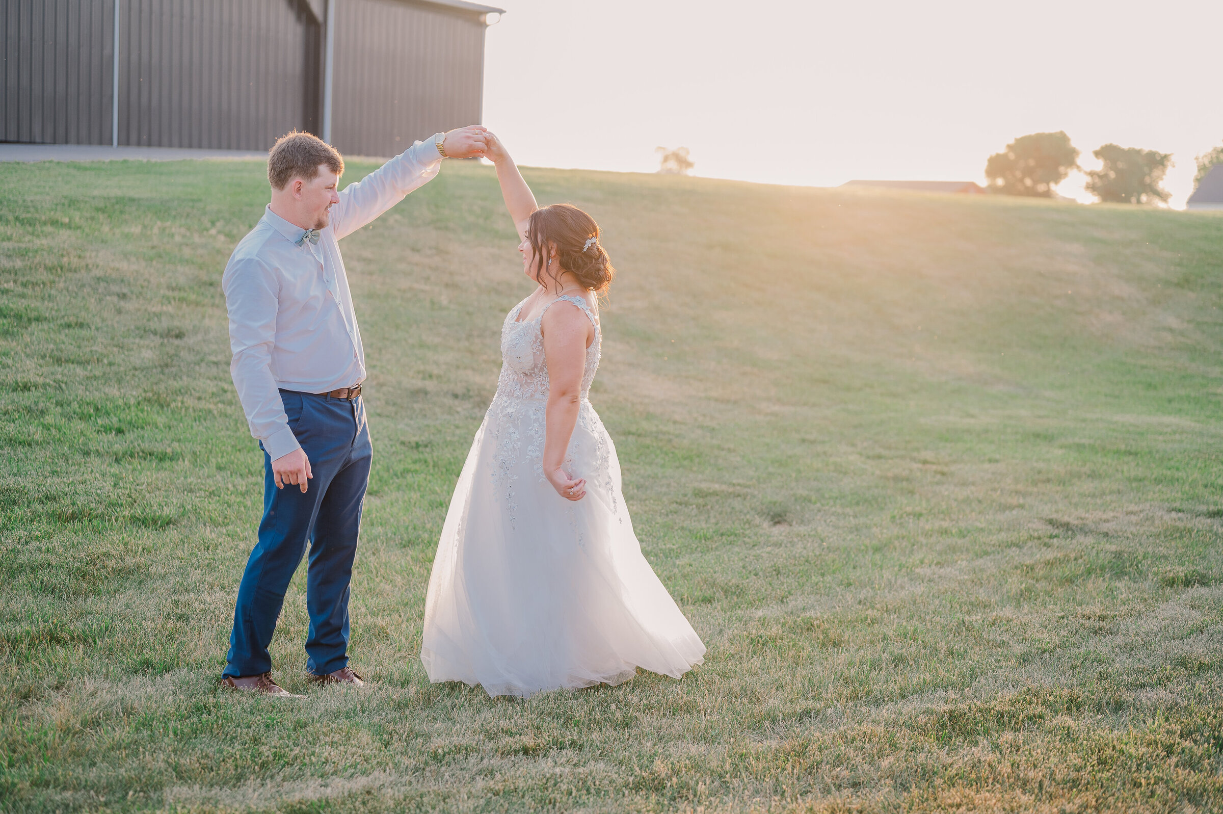 Groom twirls bride at sunset