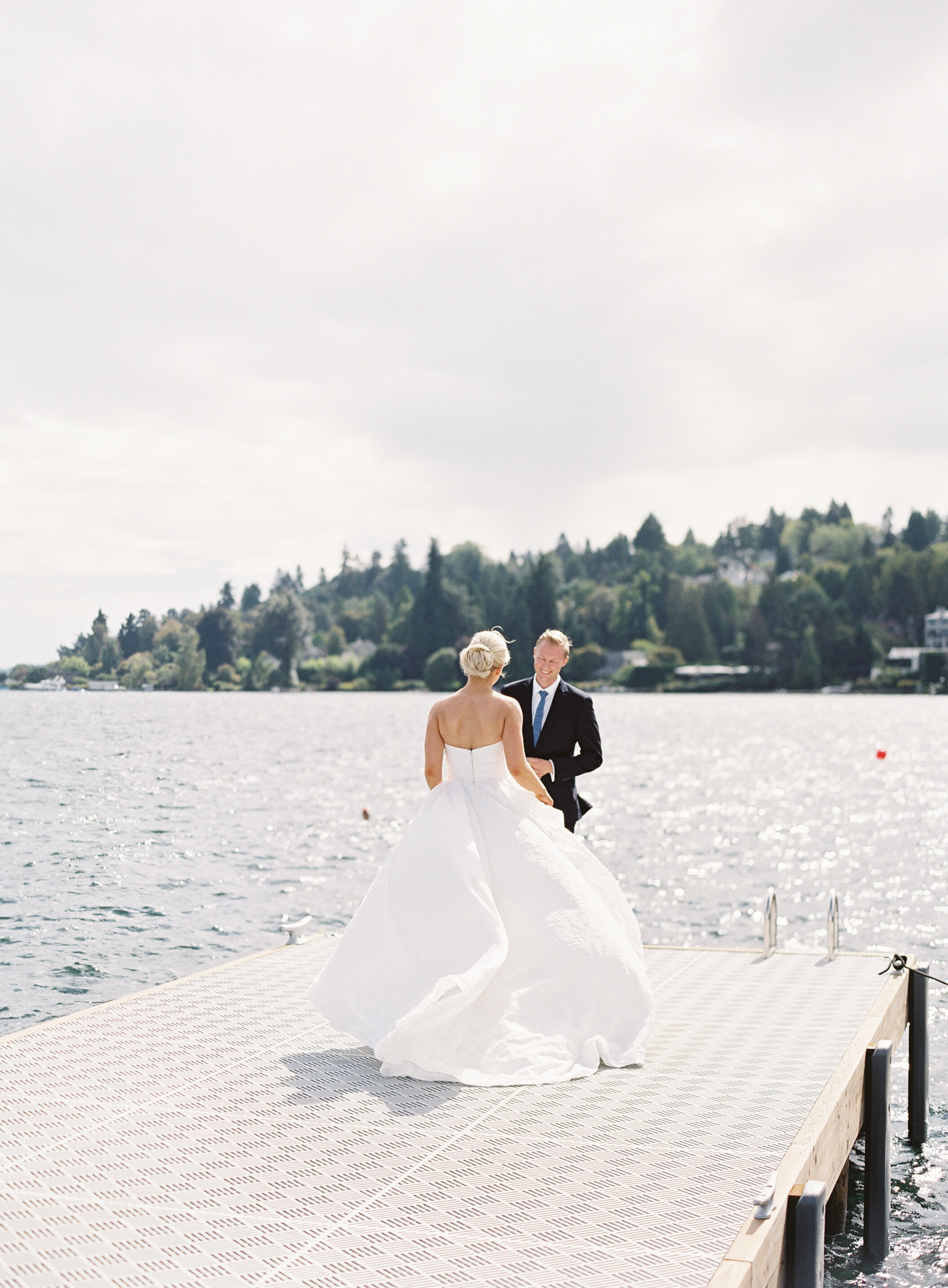 wind swept bridal gown first look moment on lake dock at seattle tennis club