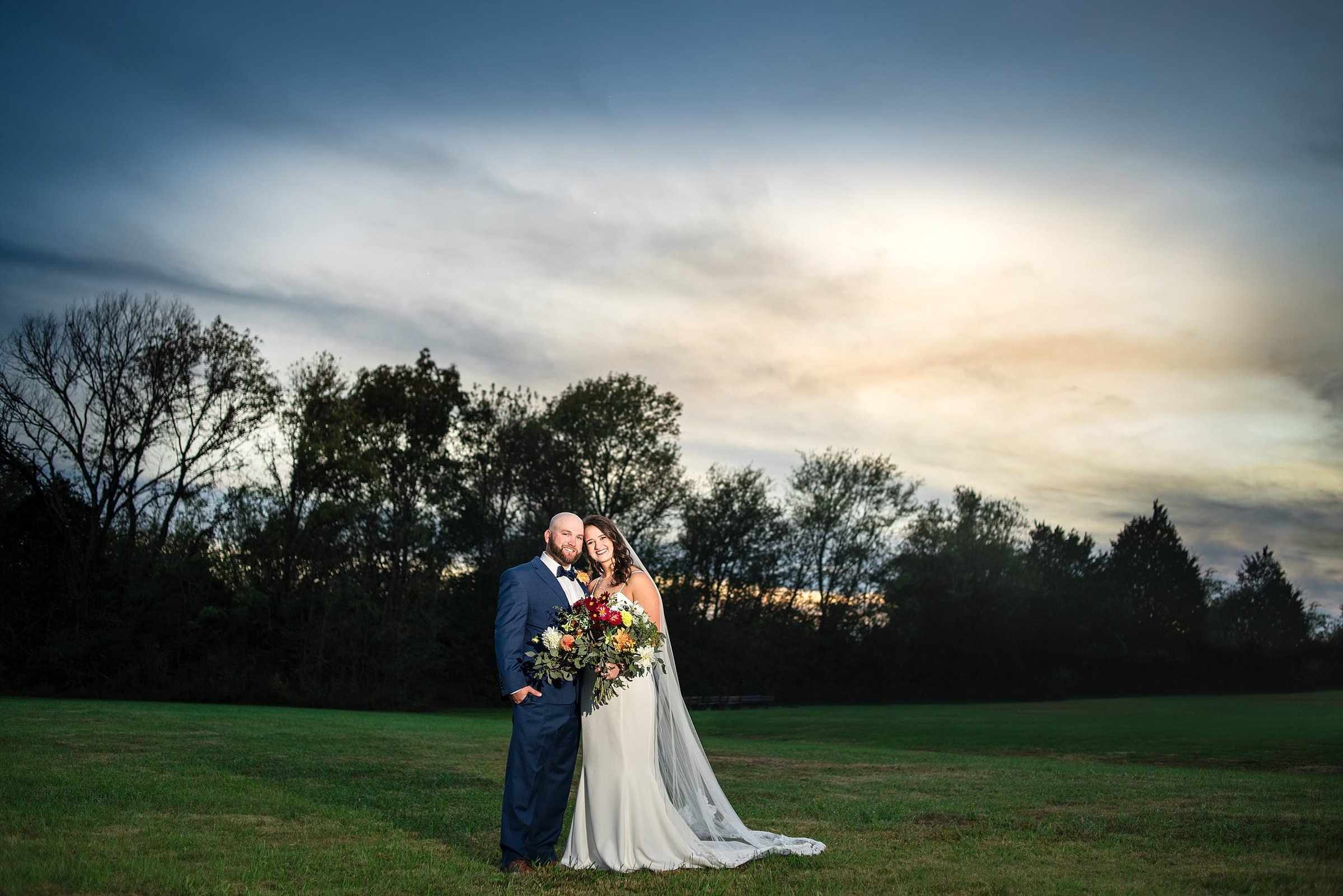 Couples portrait in grass field at sunset
