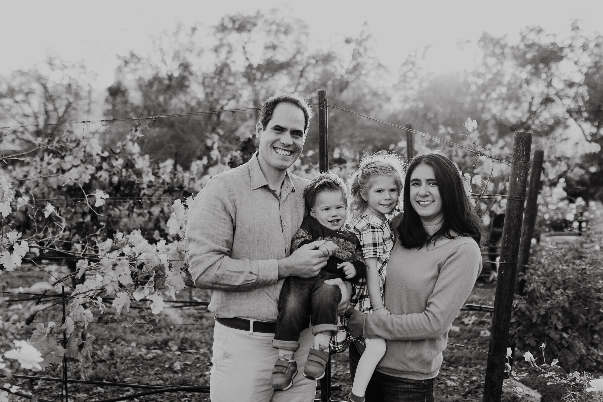 Family stands in a vineyard while the sun dips below the horizon