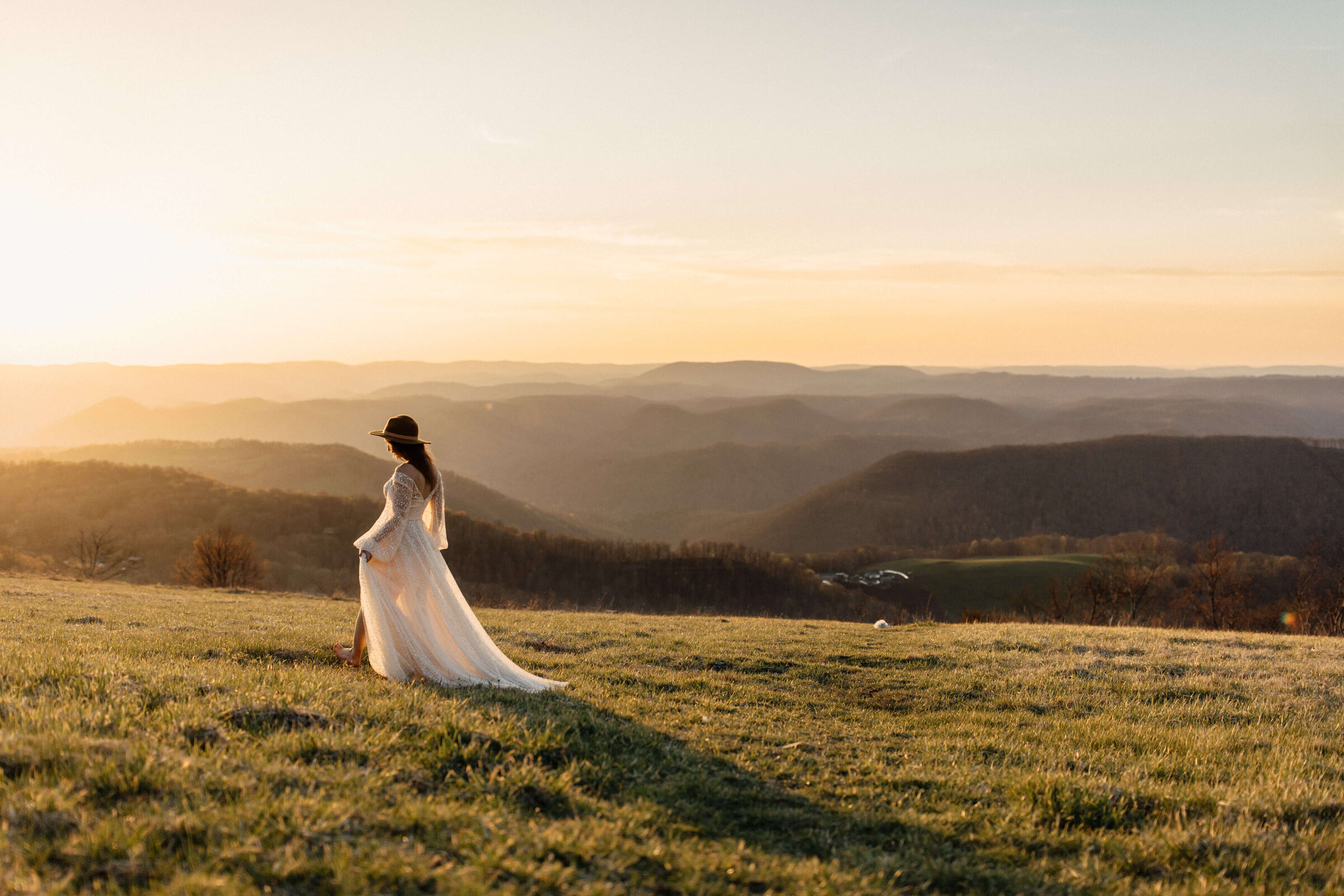 mountain elopement bride walking on mountaintop in her long dress at sunset