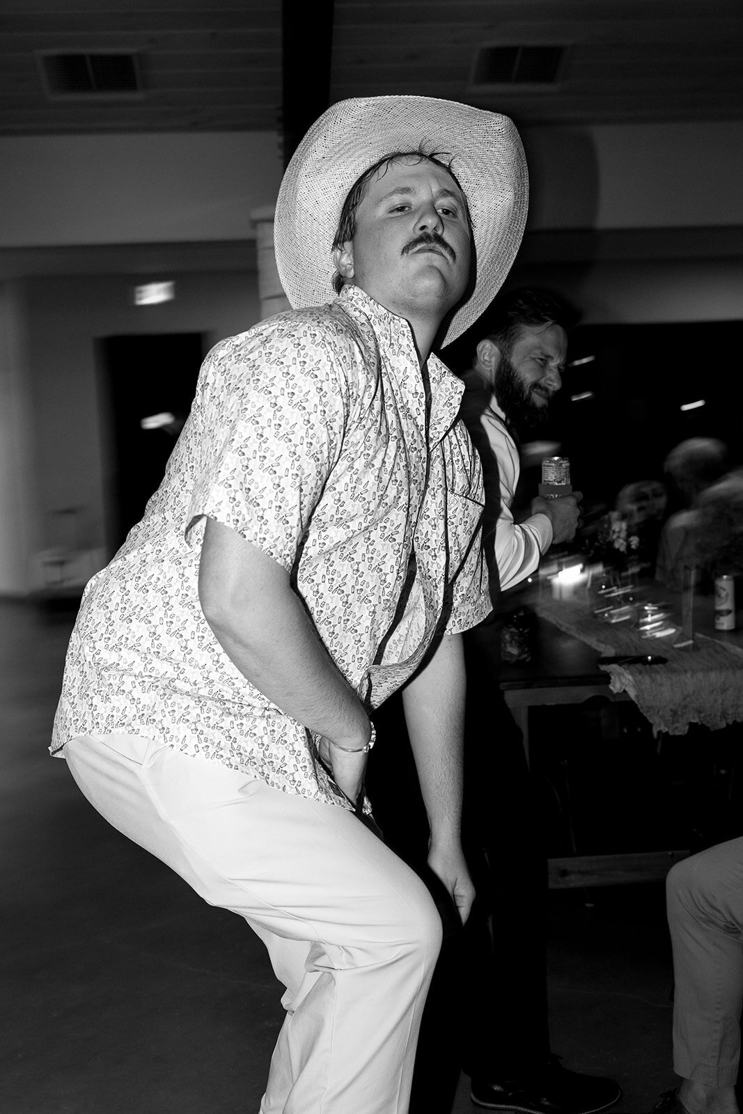 A guest in a cowboy hat dancing at a wedding reception.