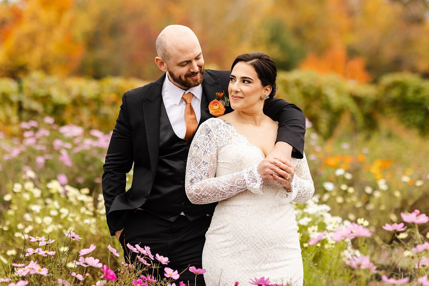 Groom slings his arm over bride's shoulder during portraits at their fall wedding at The Barn at Bradstreet Farm in Rowley, Massachusetts