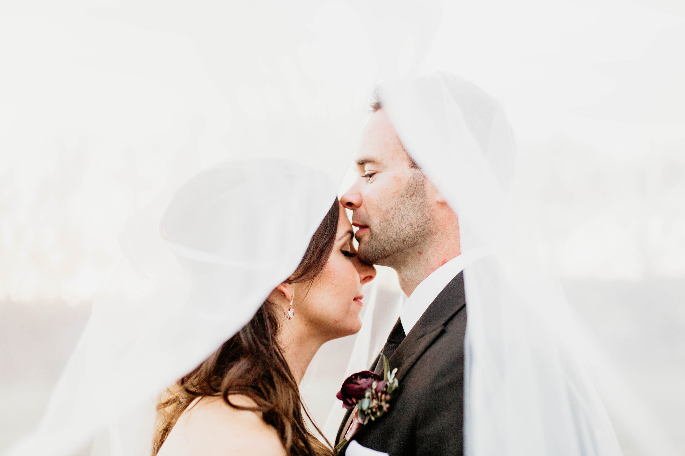 Groom kissing bride on forehead. 