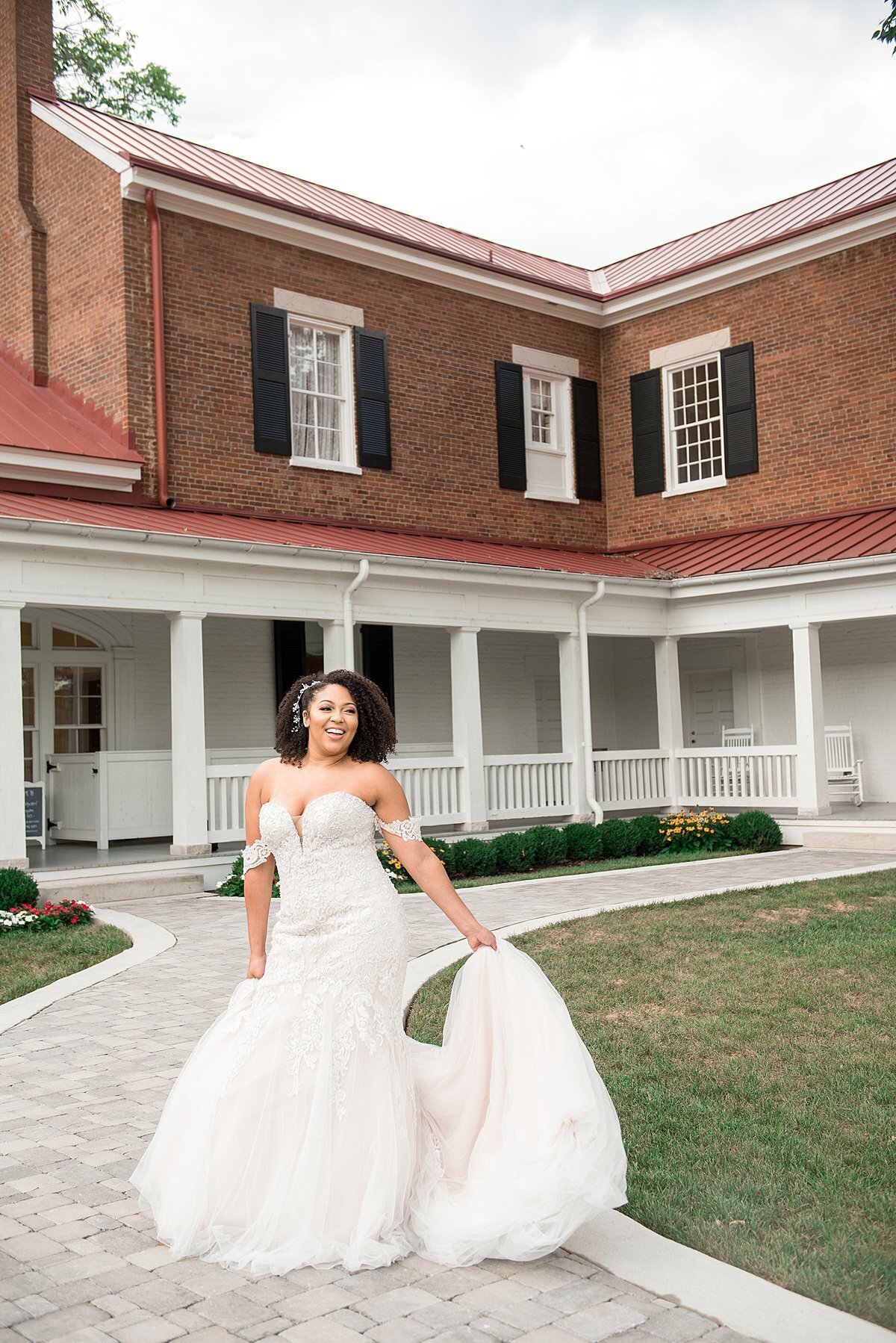 Bride holding her train and laughing with Ravenswood Mansion in the background