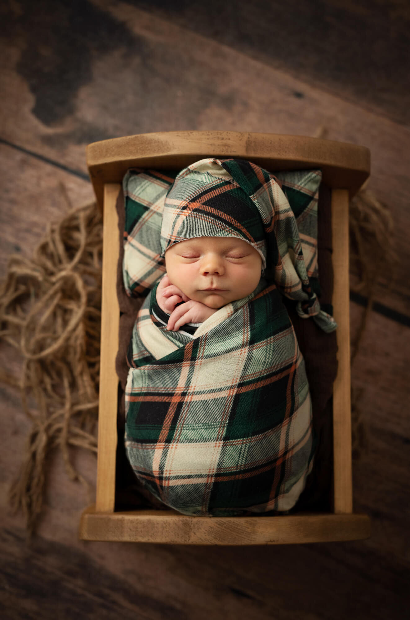 Sleeping newborn baby in plaid in a bed