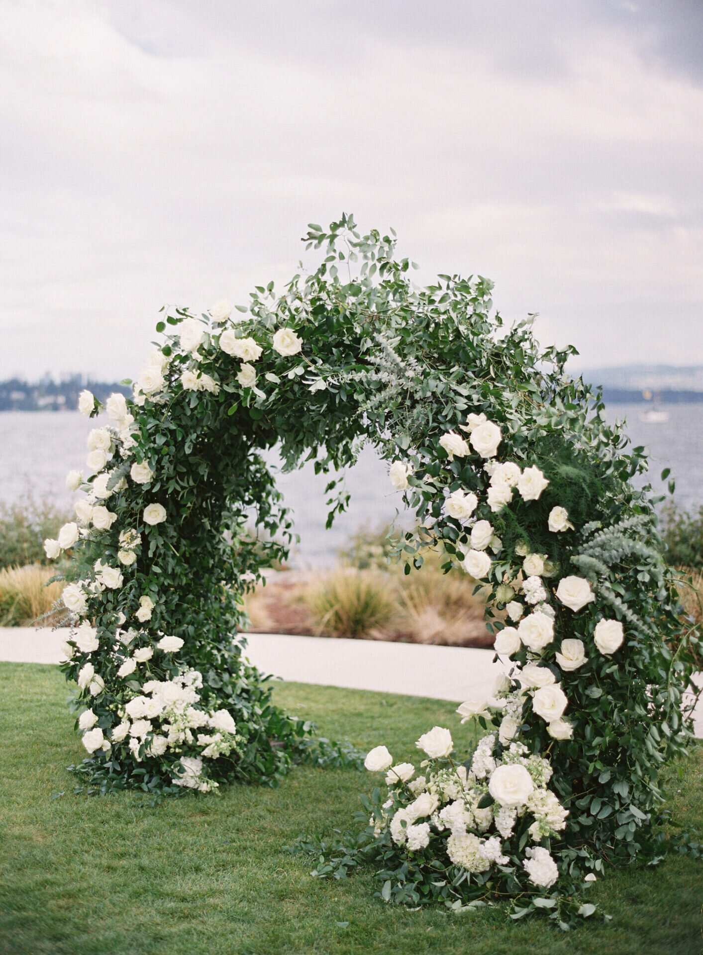 lush floral white rose rounded ceremony arch overlooking the lake at seattle tennis club