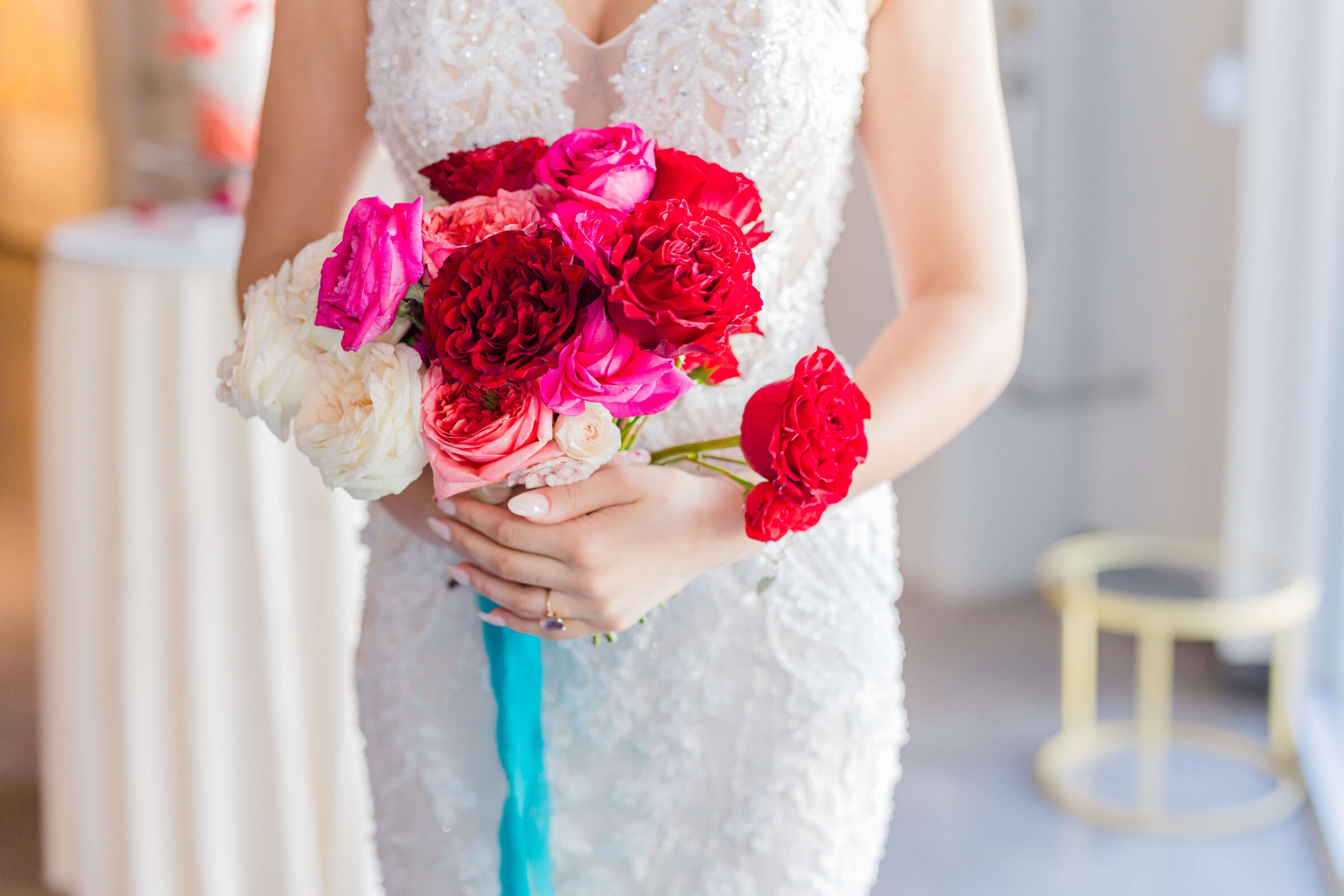A bride holding a hot pink and red bouquet