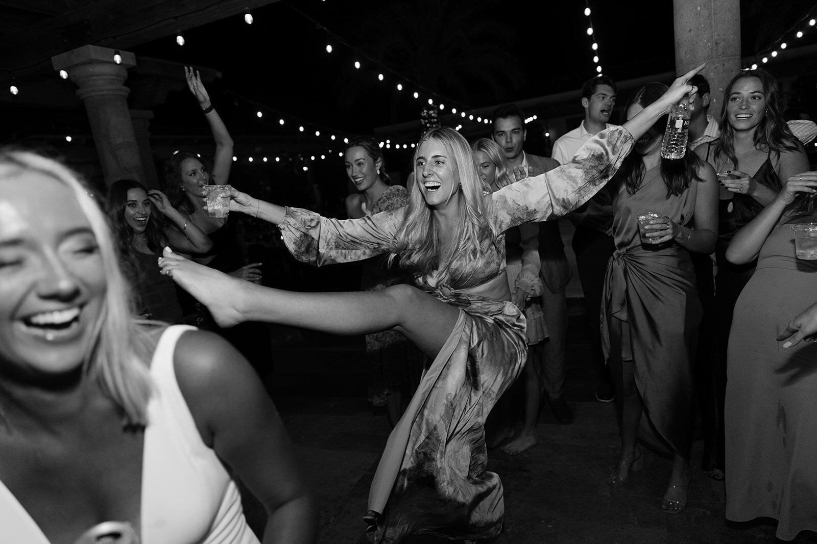 A guest at a wedding reception, dancing and kicking her leg up.