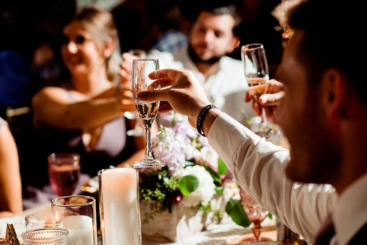 Close up photo of guests clinking wine glasses together during wedding toast