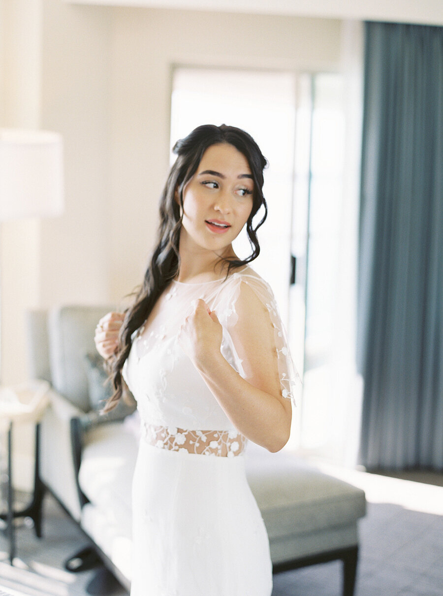 bride looks over her shoulder into the mirror at herself