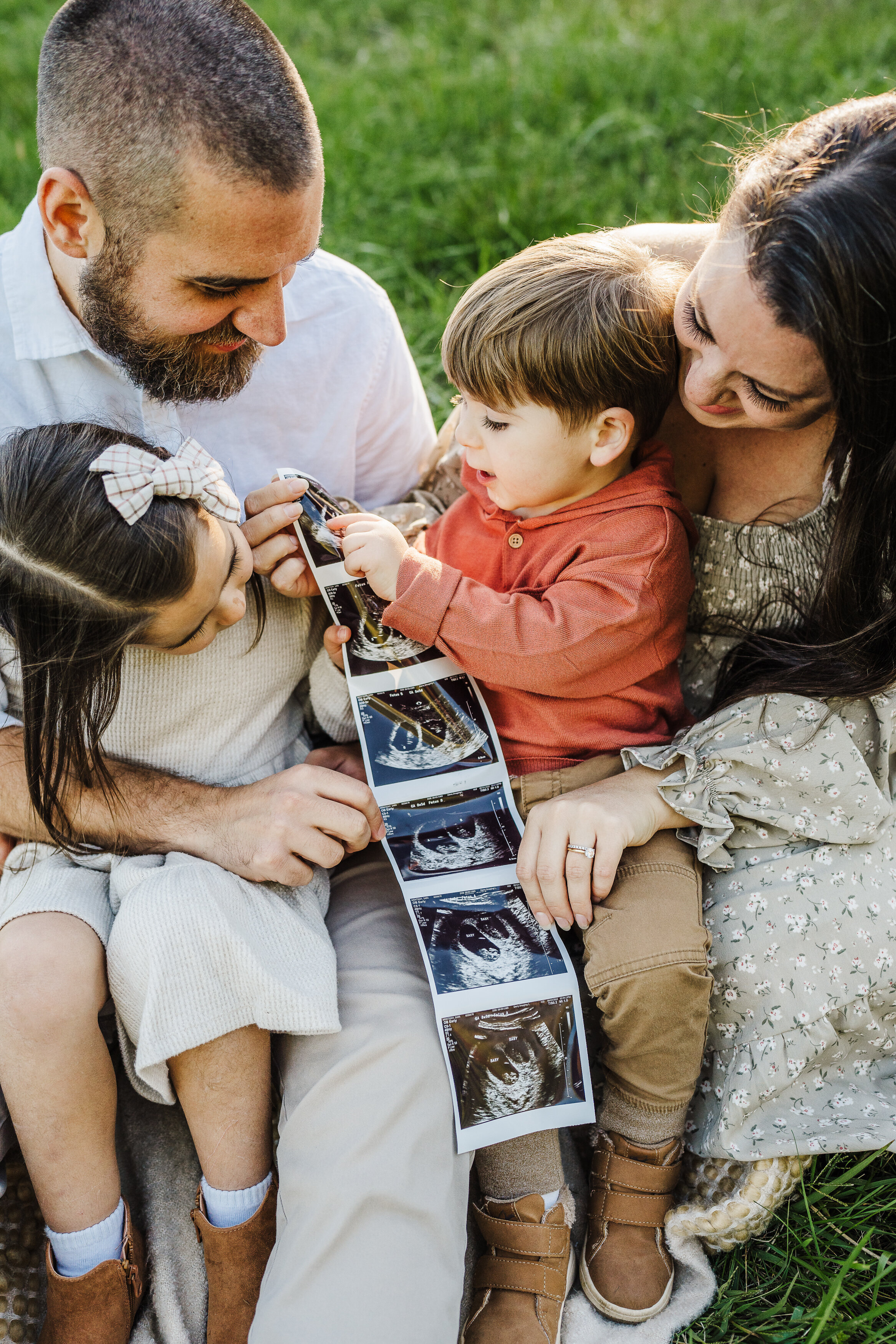 toddlers look at ultrasound pictures during pregnancy shoot