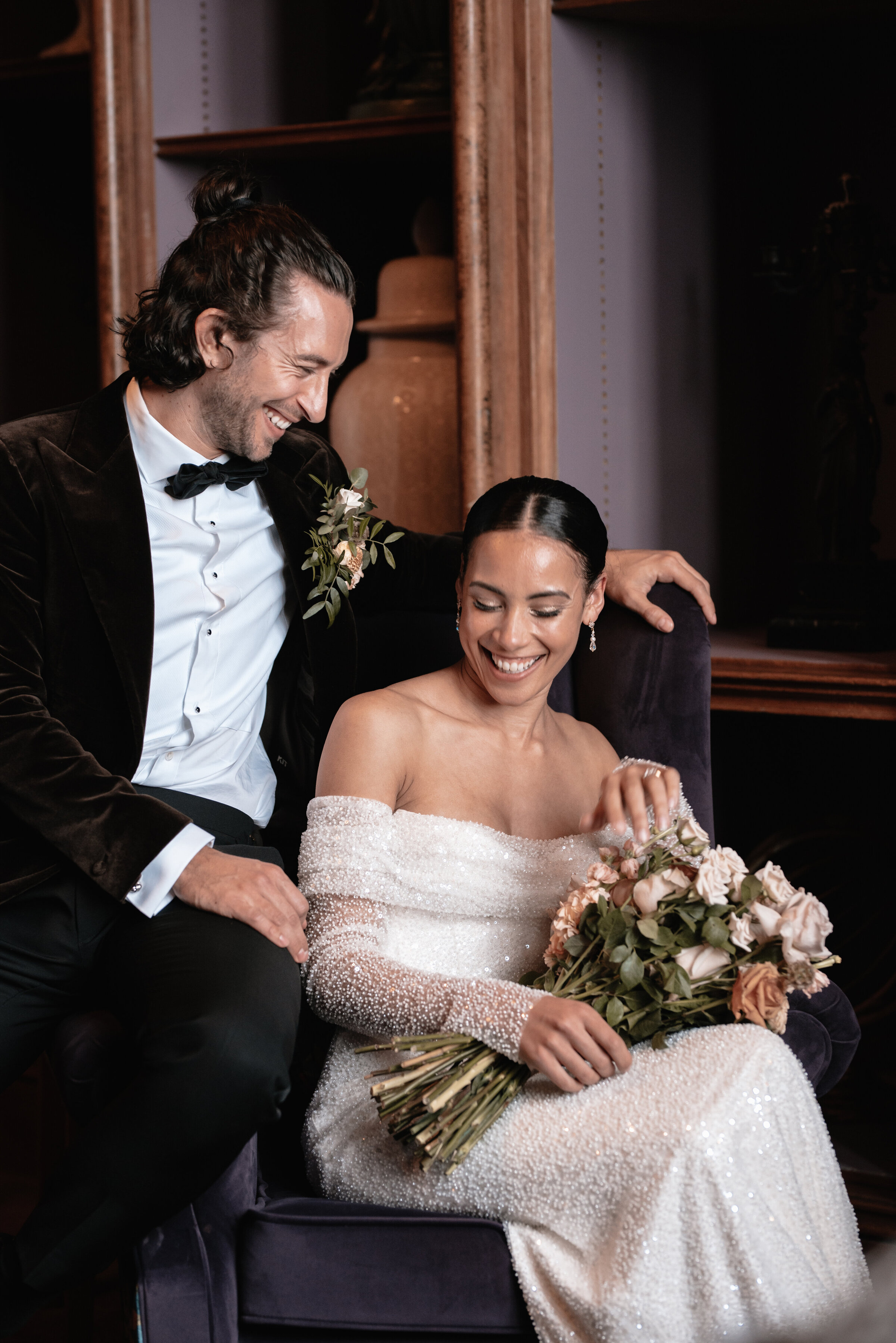 Bride and Groom seated together on chair exchanging a laugh