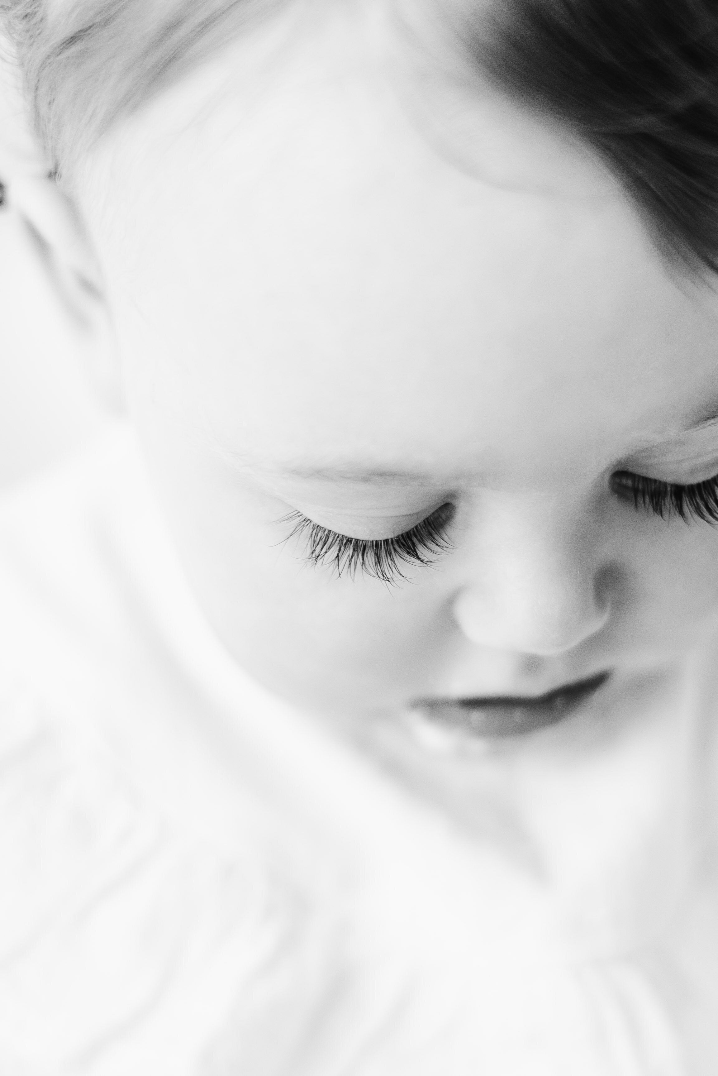 Little girl looking down with long eye lashes at cake smash photoshoot in Billingshurst