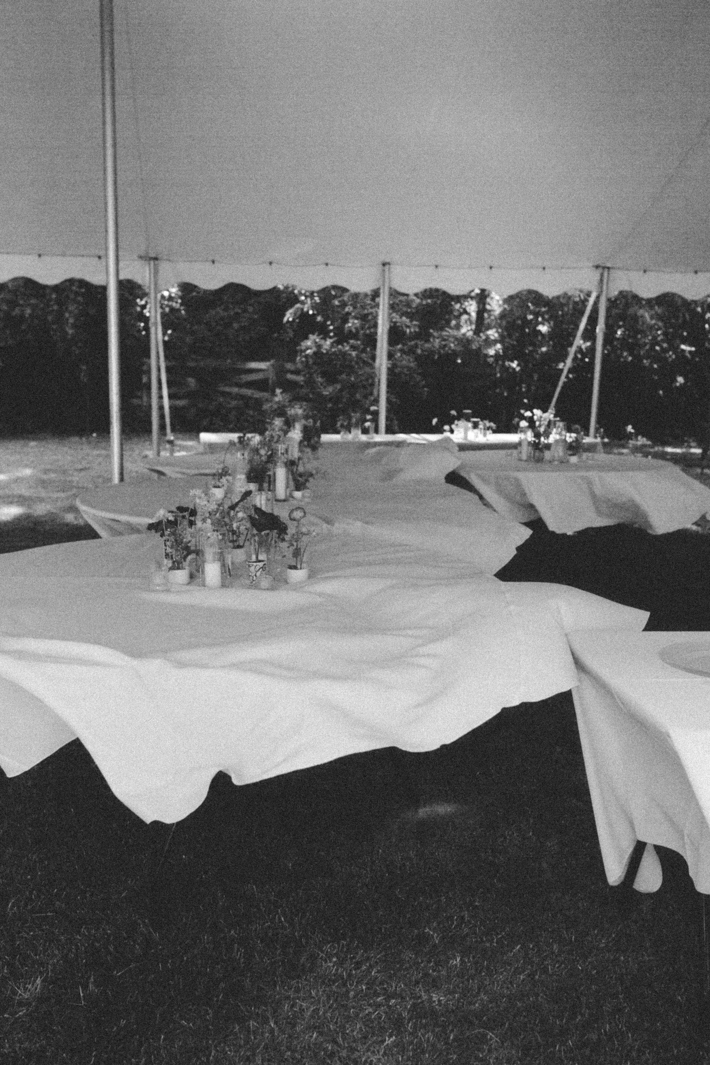 Backyard wedding tablescape blowing in the wind, captured in black and white documentary style by Emily Ambie.