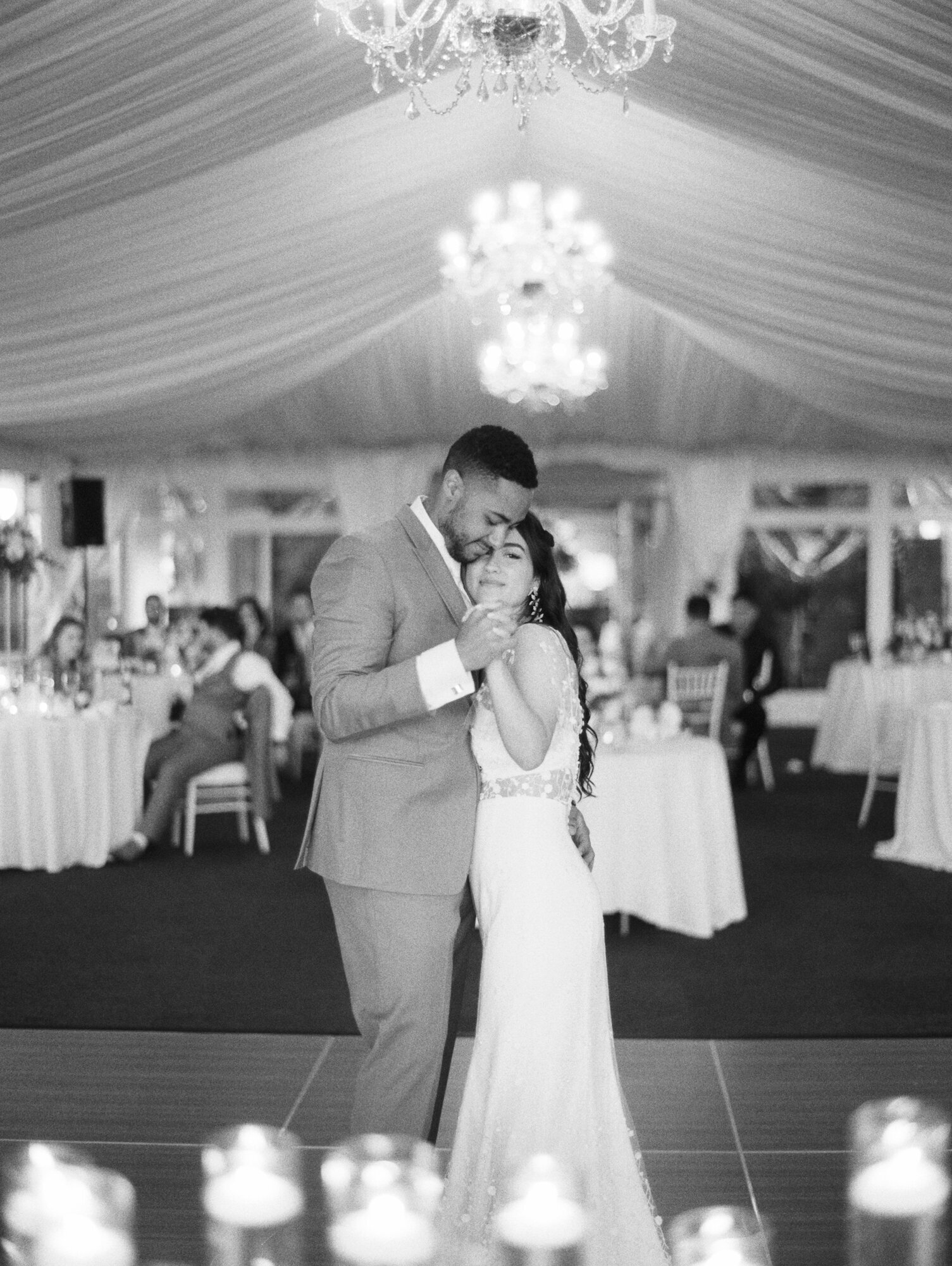 bride and groom have their first dance under white tent bw photo