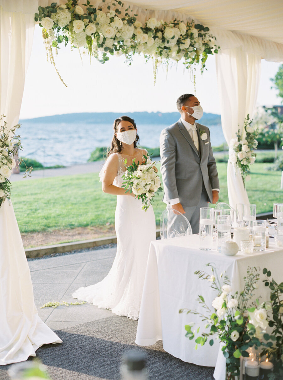 bride and groom at head table standing wearing covid masks