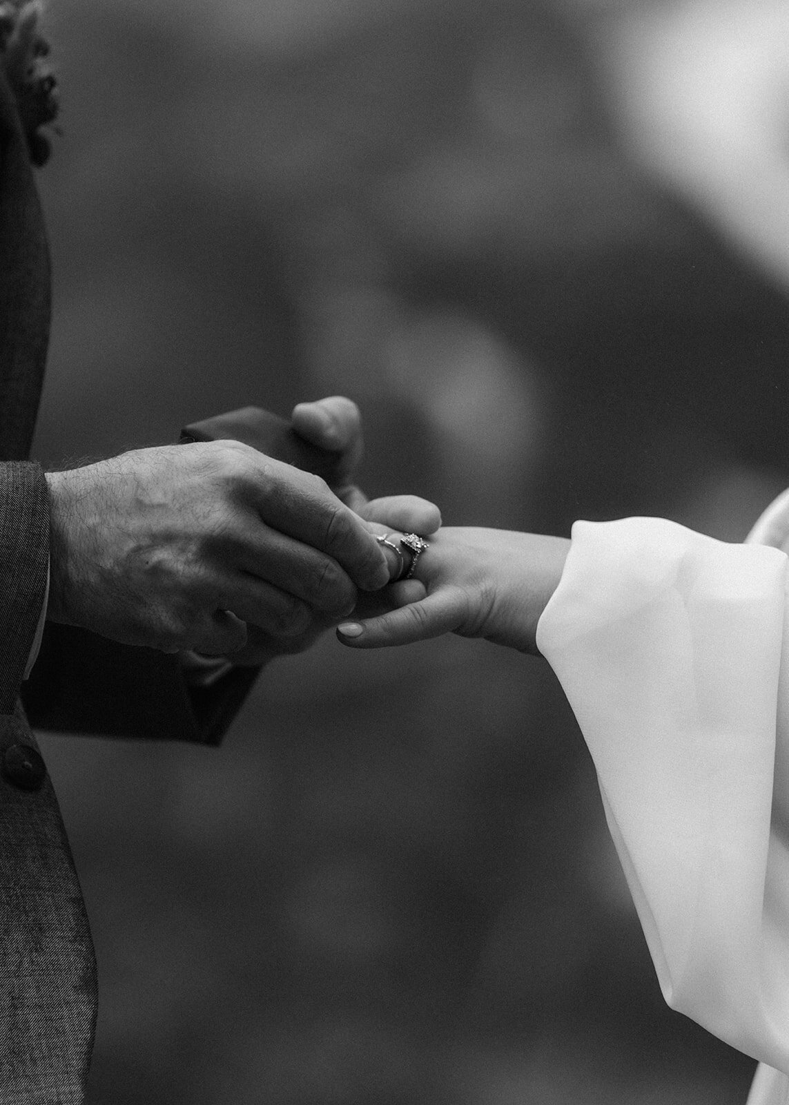 a close up, black and white shot of a bride and groom exchanging rings during their adventure elopement