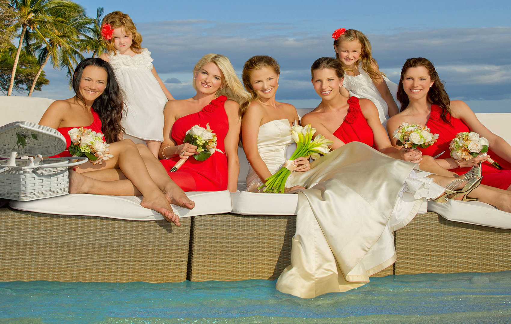 bride and her bridesmaids wearing red dresses  with white flowers.
