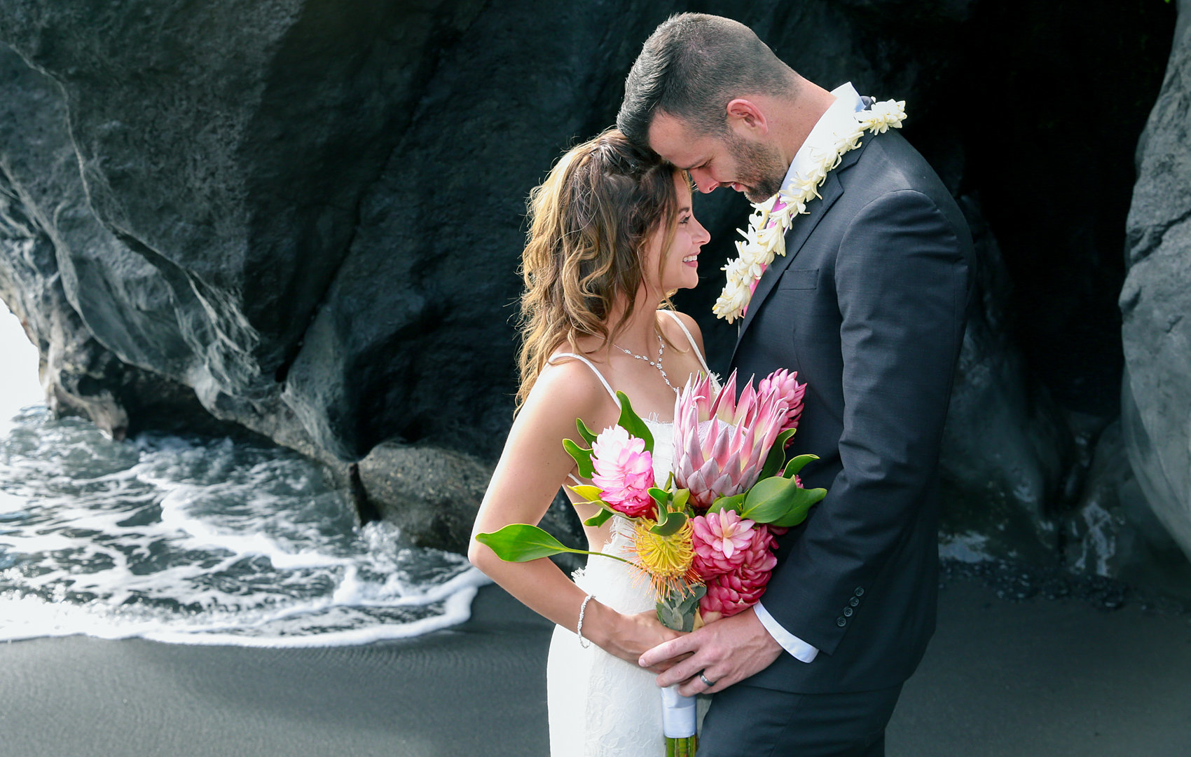 Wedding couple kissing on black sand beach.