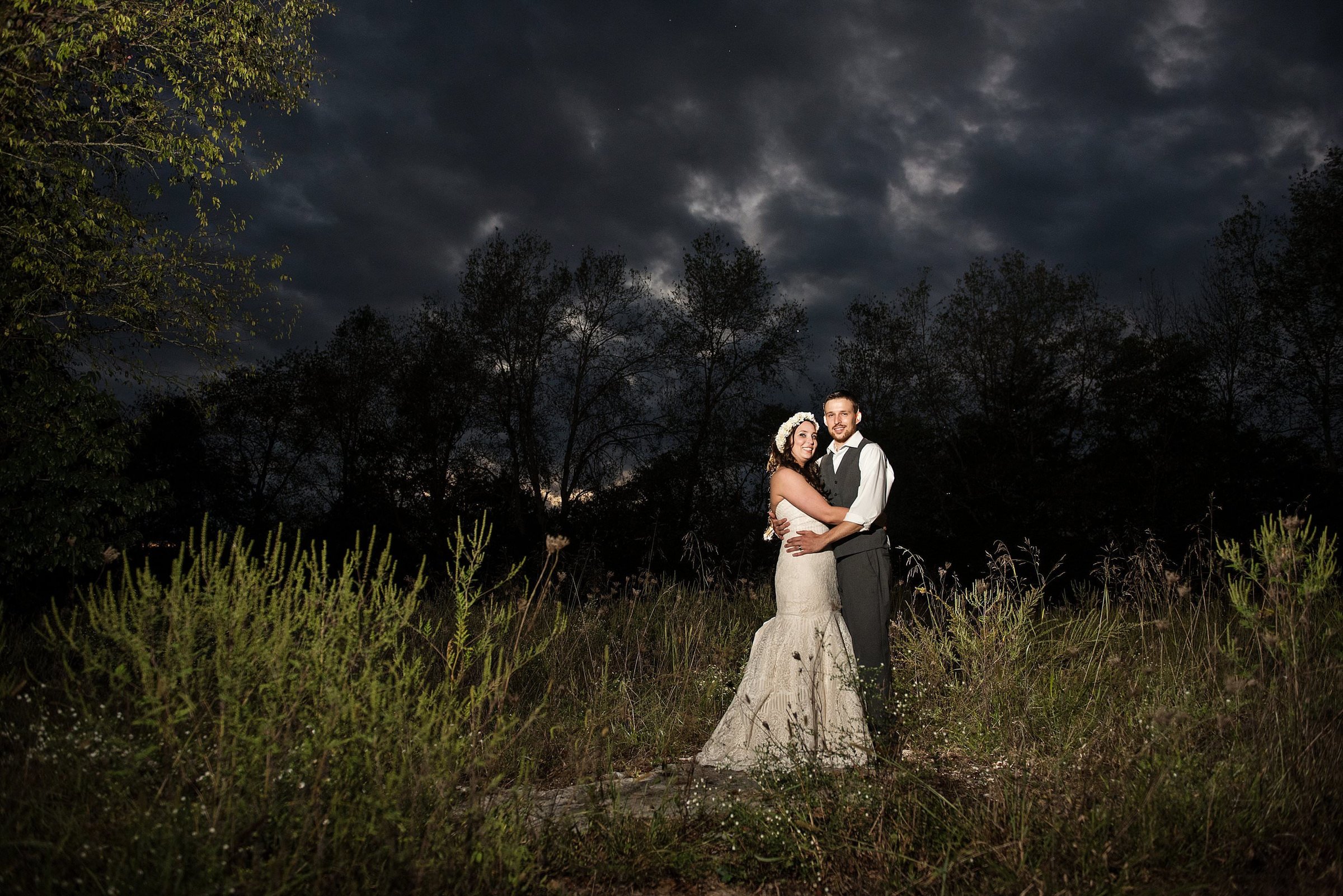 Bride and groom night time portrait under a stormy sunset