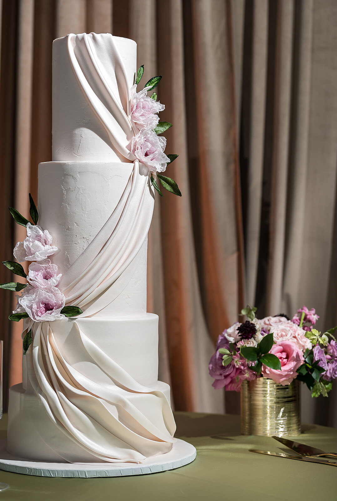 Modern four-tier white wedding cake with draped fondant and delicate sugar florals displayed against velvet draping at The Kent in downtown Memphis, designed for a luxury celebration by Wells Design Co.