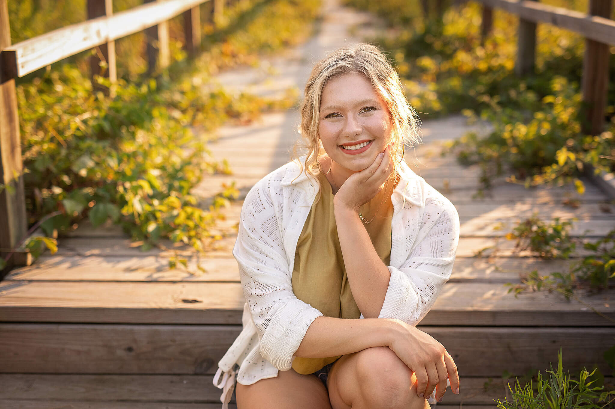 high school senior girl sitting on wood steps to a bridge
