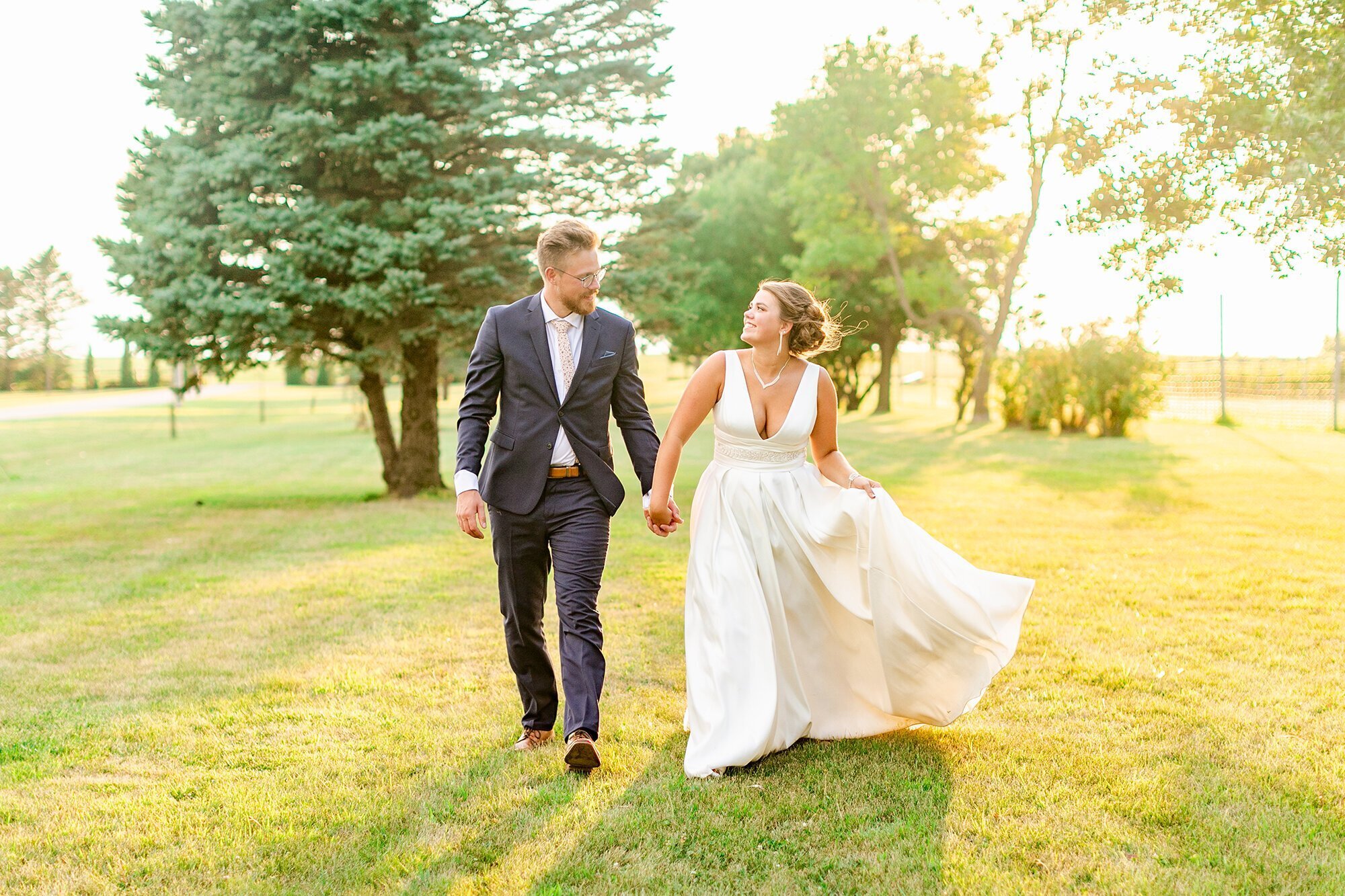 Bride and groom holding hands and running in a park, taken by minneapolis wedding photographer