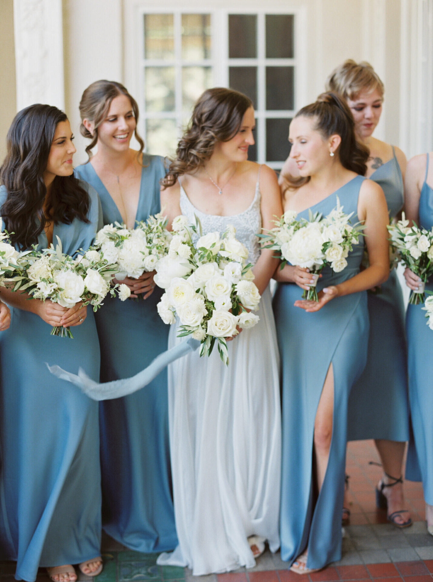 blue and white bridesmaids at villa wedding in CA holding white rose bouquets