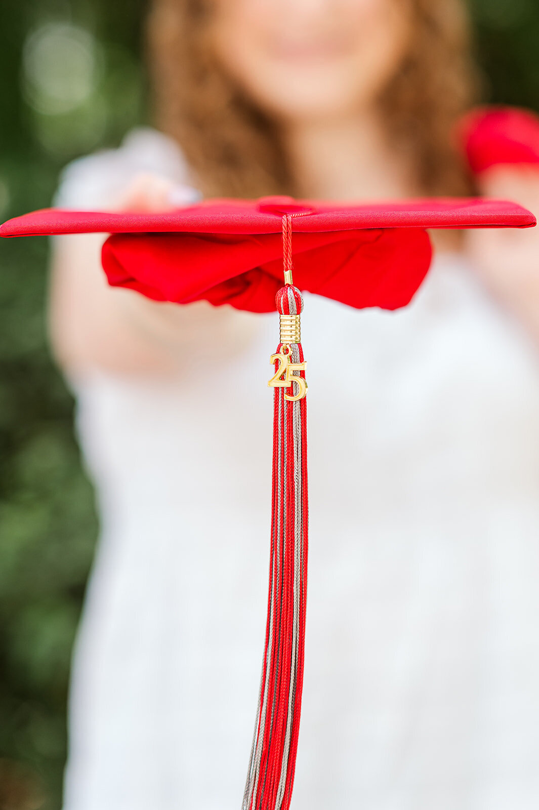 Artistic close-up of a red graduation tassel on a senior gown