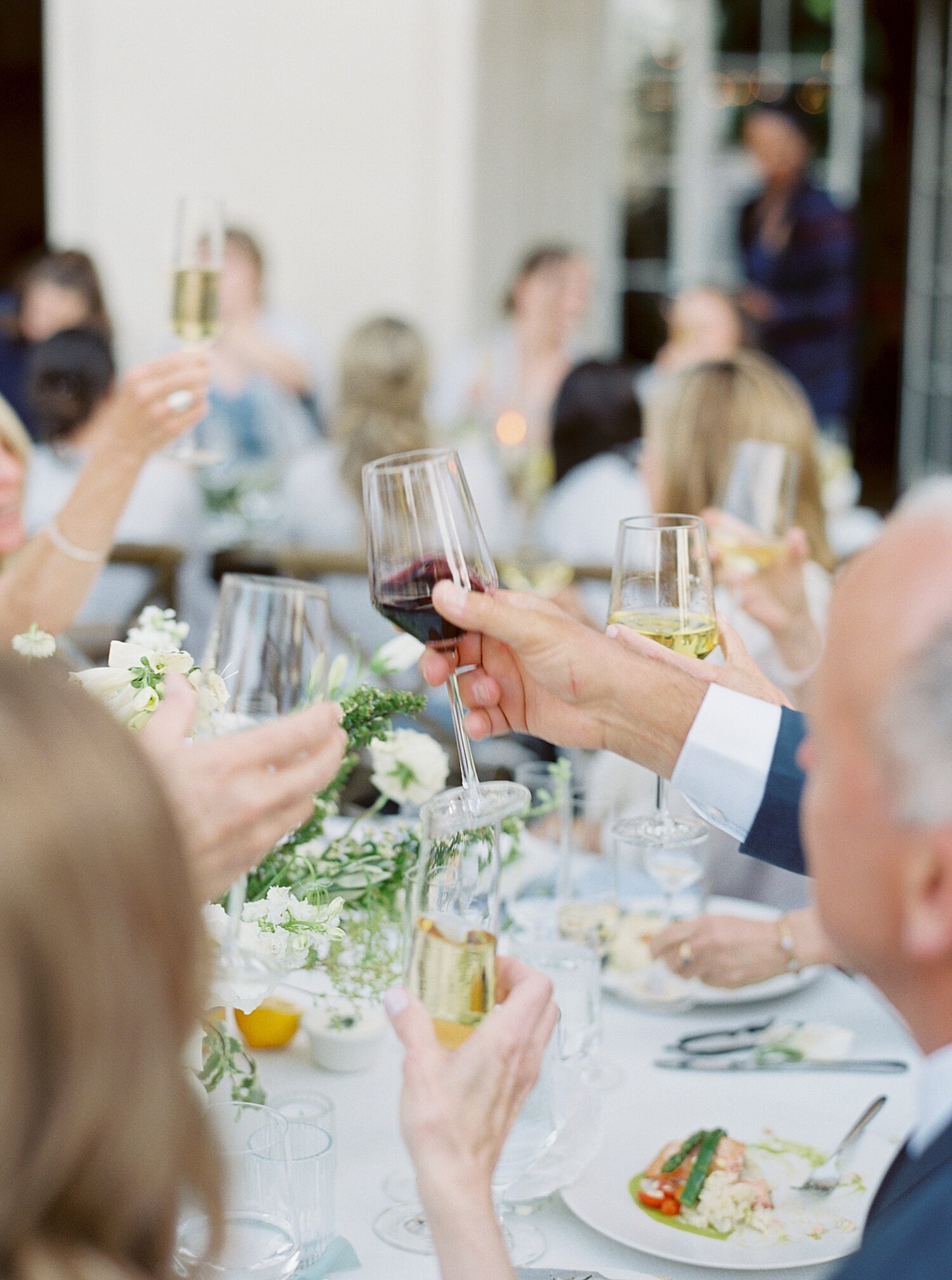 hands and wine glasses in the air cheers at wedding reception