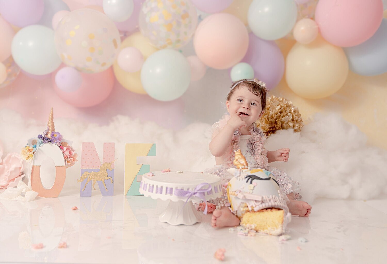 Little girl photoshoot with color balloons and a big cake