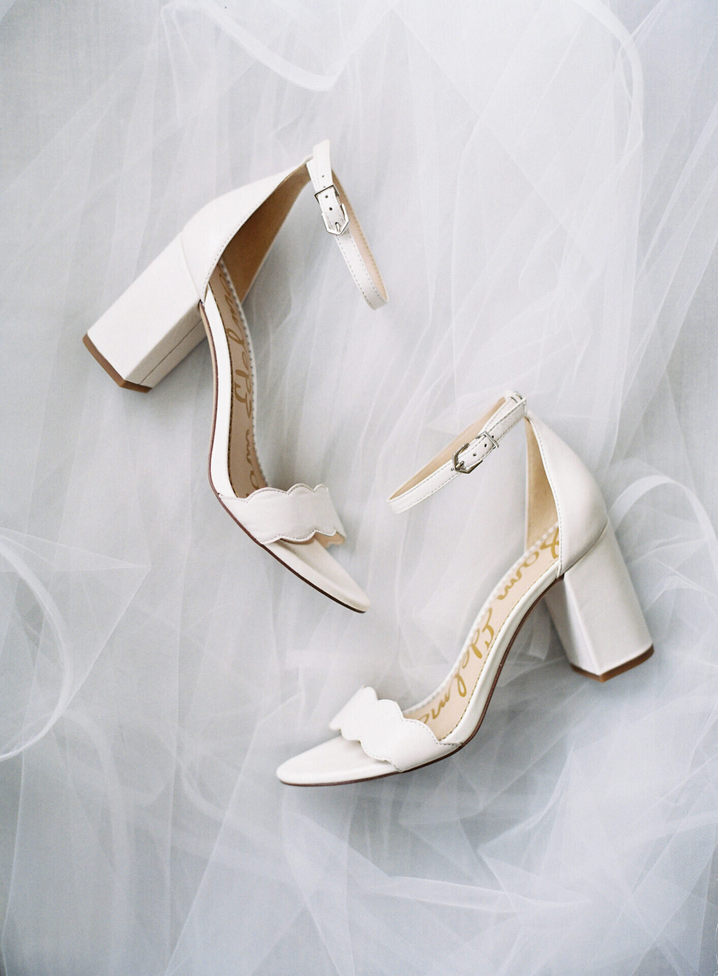 sam edelmen white bridal heels laying on veil