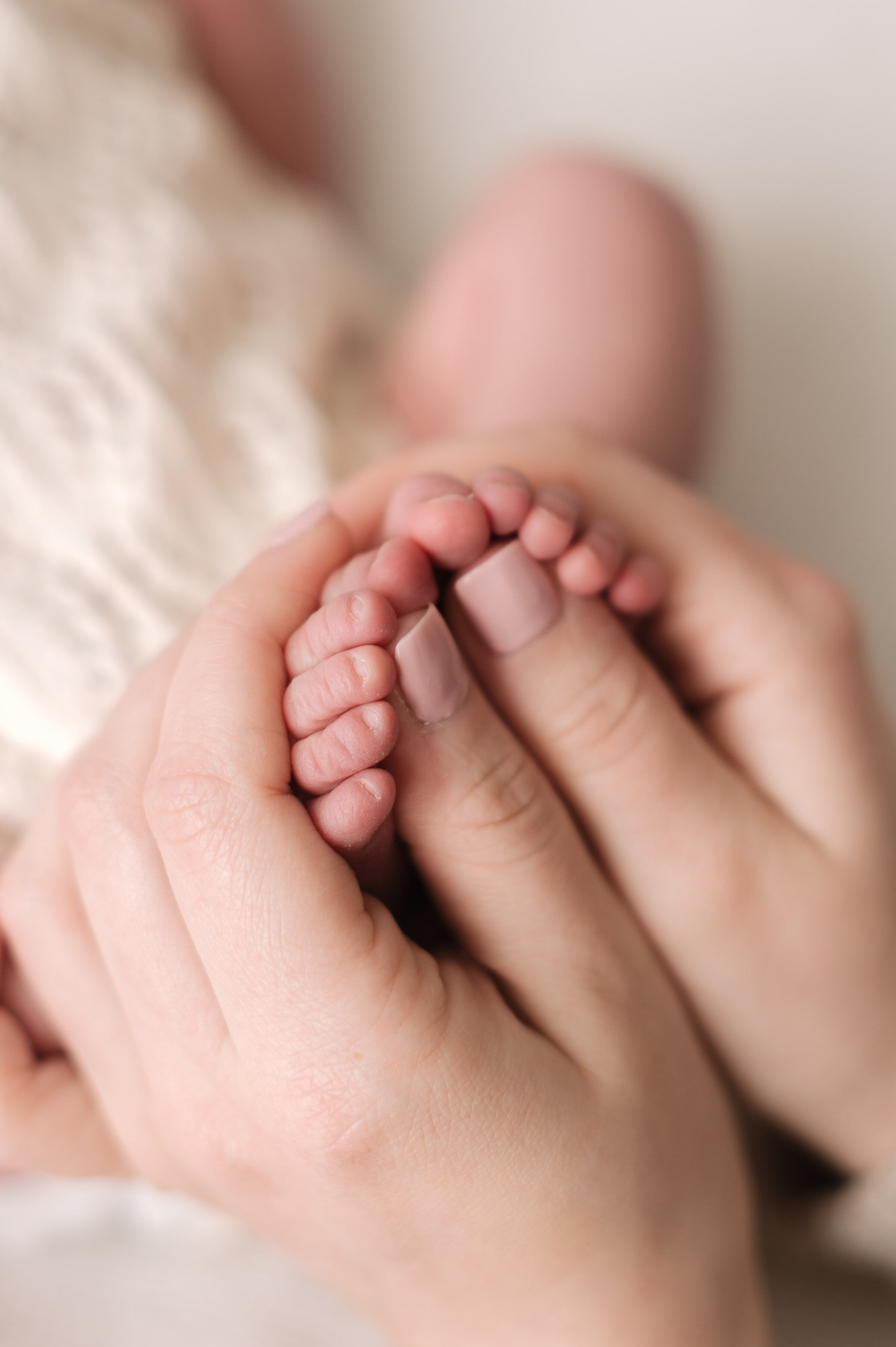 Mums hands holding both her newborn babies toes at Billingshurst newborn photoshoot