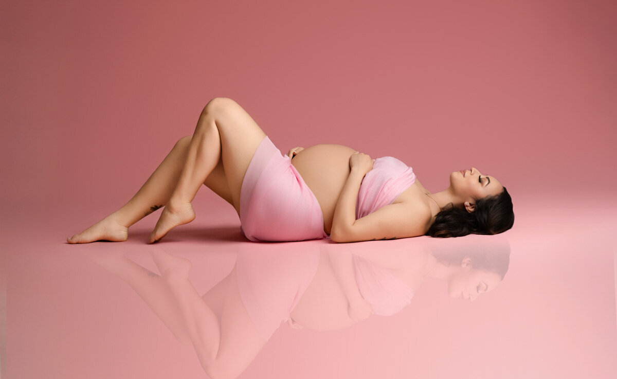 Maternity portrait of a woman on a beach in orlando wearing a white lace gown