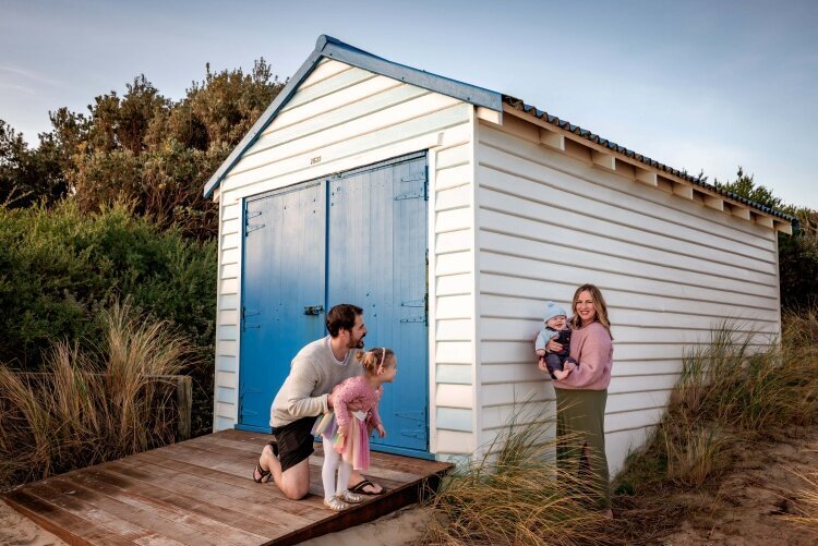 Family of four playing peekaboo around a blue and white beach box by Melbourne Family Photographer Kate Cashin