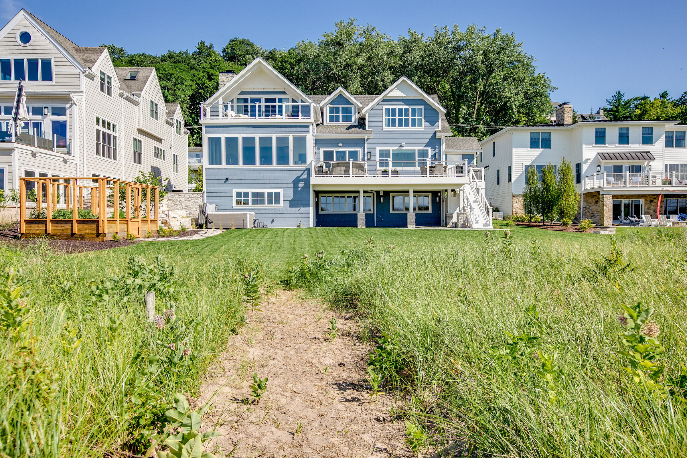 A scenic shot capturing custom homes in the distance, framed by wild grass in the foreground. The natural landscape contrasts beautifully with the carefully designed architecture, creating a harmonious blend of nature and luxury.